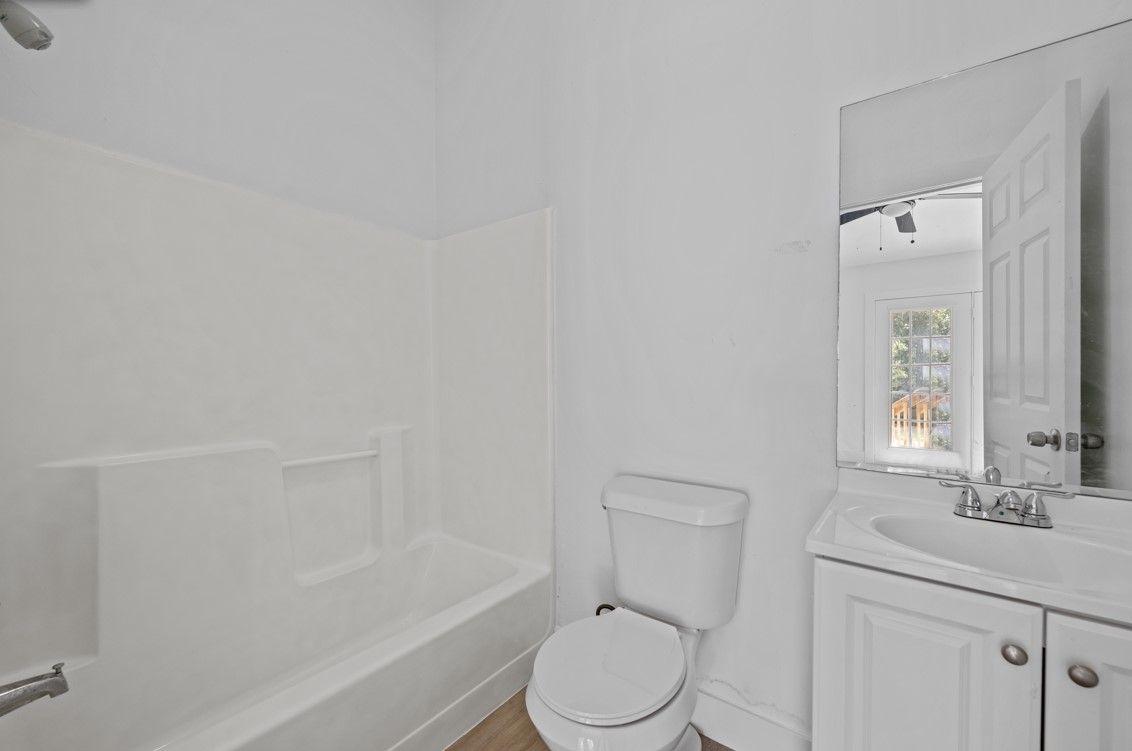 A bathroom with a toilet , sink , bathtub and mirror.