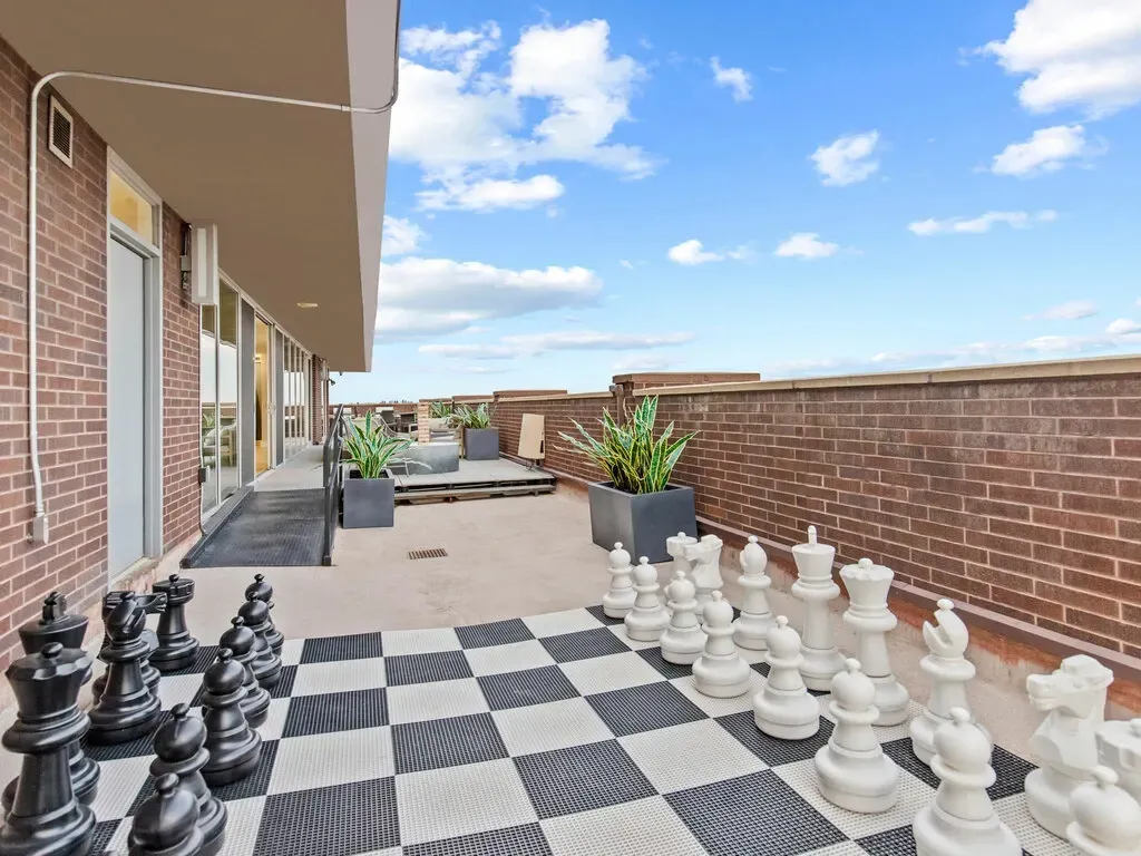 Outdoor chess set on a rooftop patio with black and white pieces on a checkered board