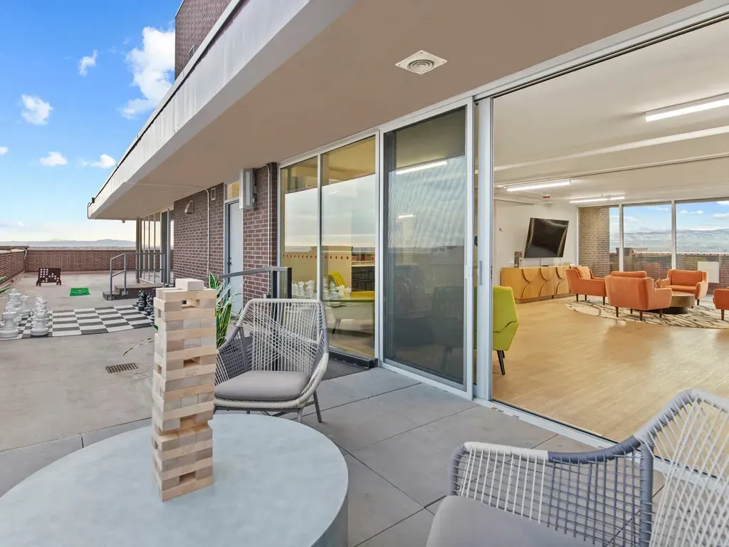 Outdoor patio beside a modern glass-walled lounge with wicker chairs and desert views