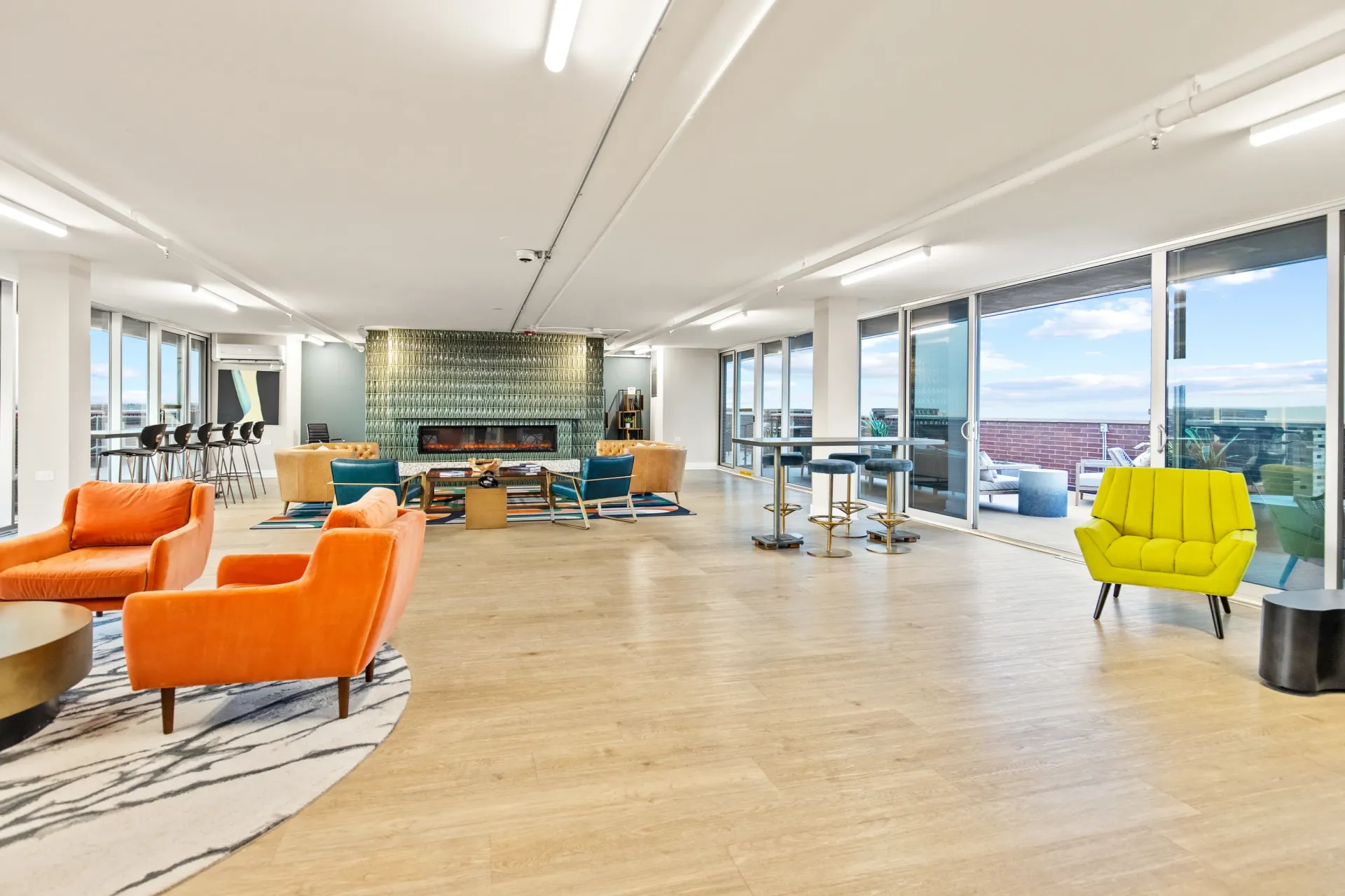 Modern lounge area with orange armchairs, bar stools, and a fireplace.