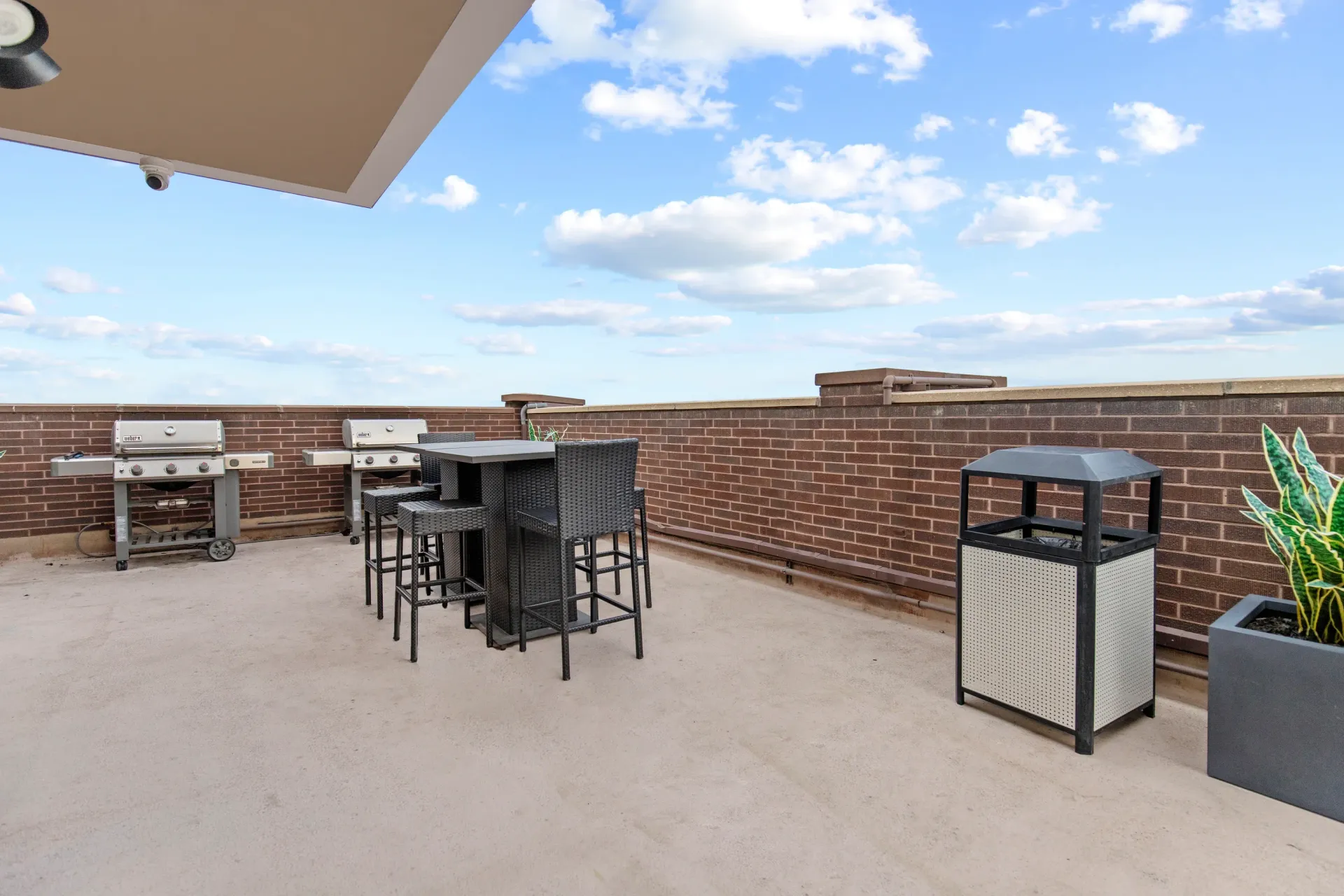Rooftop patio with grills, bar seating and trash receptacle.