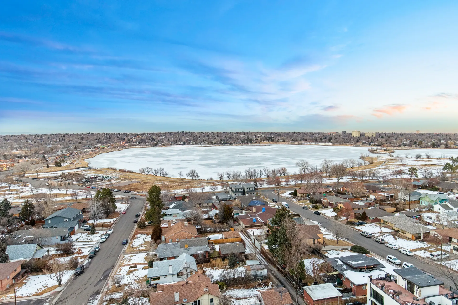 Aerial view of a suburban neighborhood with a frozen lake in the background.