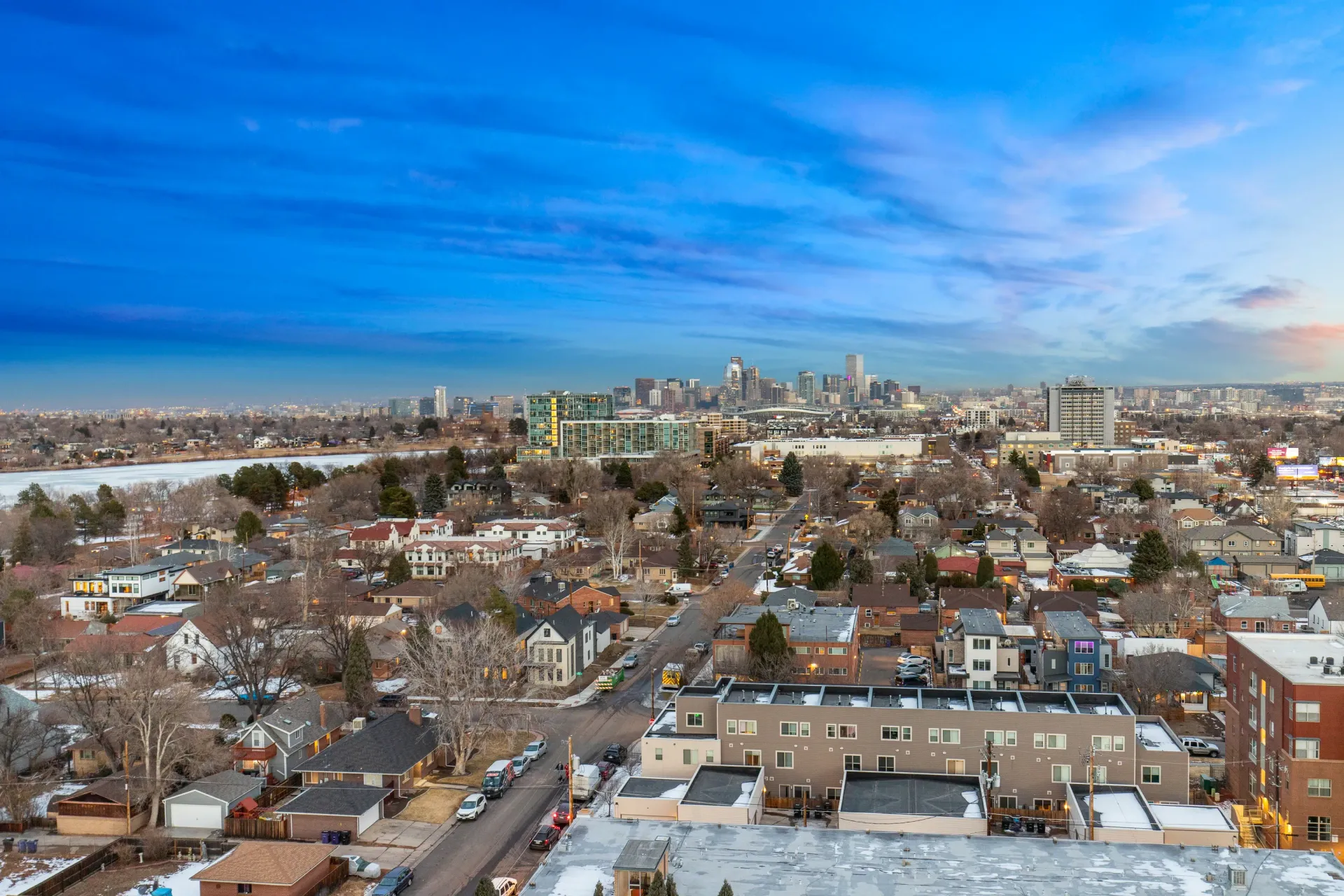 Aerial view of a city skyline with a body of water in the foreground and residential buildings.
