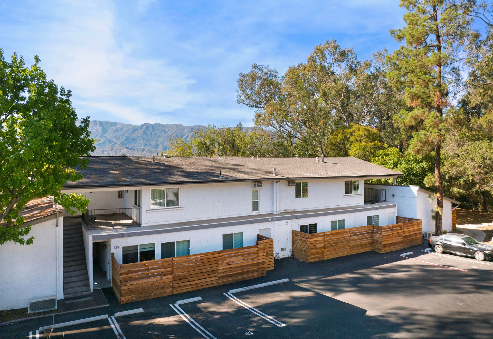 White two-story building with brick accents and mountain backdrop under a blue sky