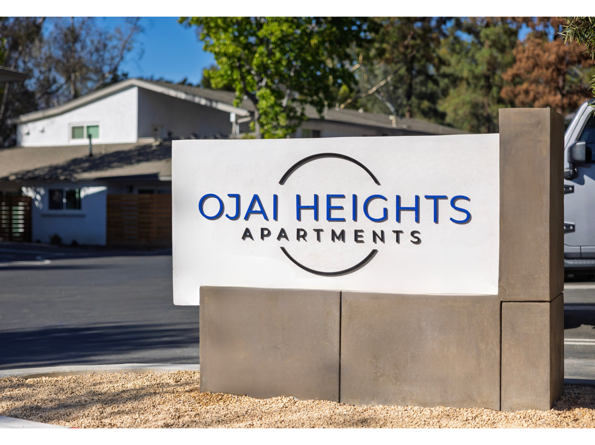 Ojai Heights Apartments sign in front of a building and trees