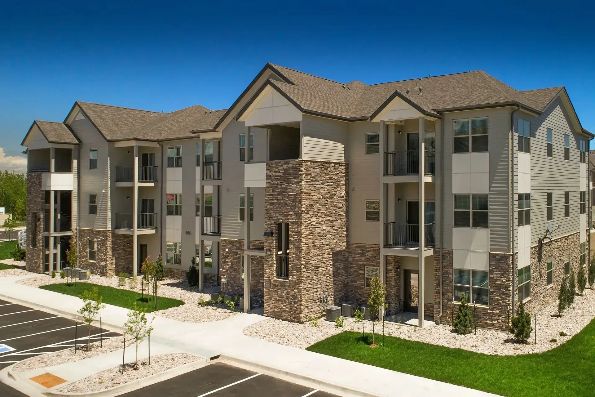 Exterior view of a modern apartment building with balconies and stone accents.
