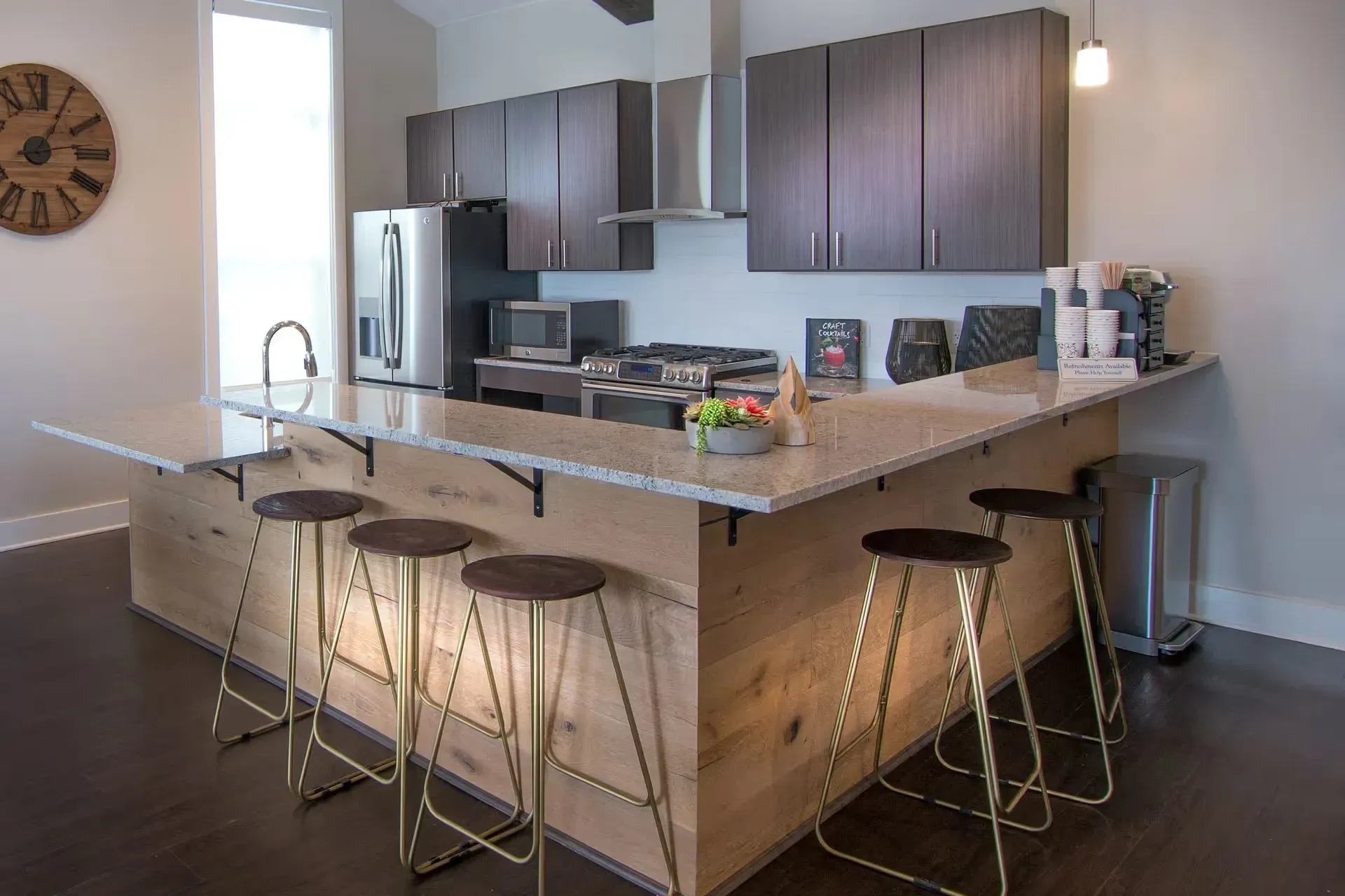 Modern kitchen island with granite countertop, stainless steel appliances, and bar stools.