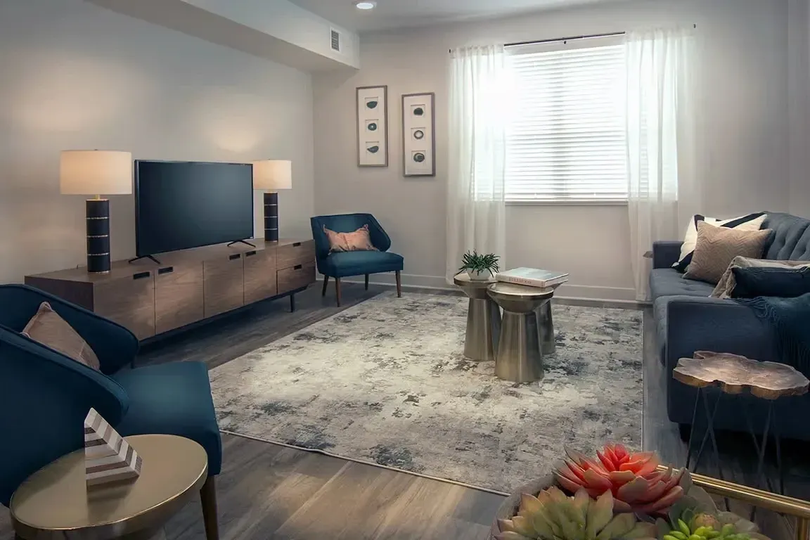 Stylish living room with blue sofa, armchairs, coffee tables, and TV.