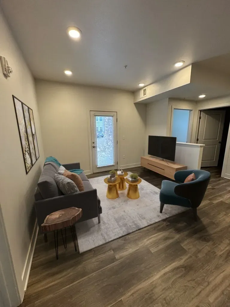 Living room with a grey sofa, accent chair, coffee tables, and a rug.