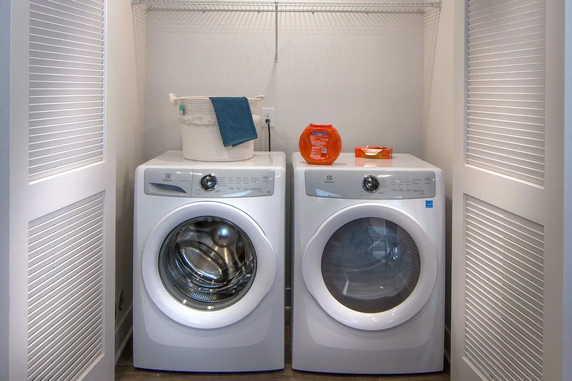 Washer and dryer set in a laundry closet with louvered doors.