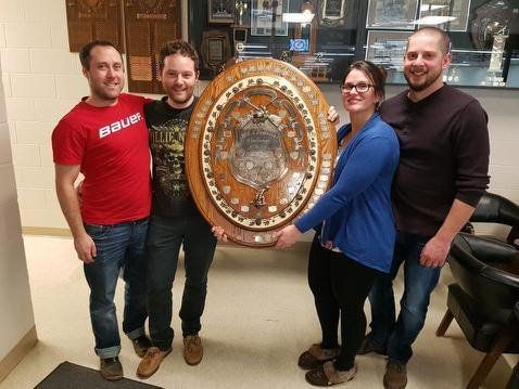 A group of people are posing for a picture while holding a trophy.