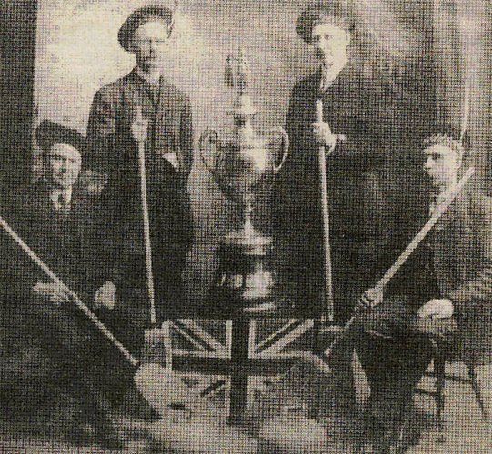 A group of men are posing for a picture with a trophy in the background.