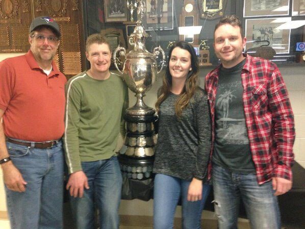 A group of people posing for a picture in front of a trophy