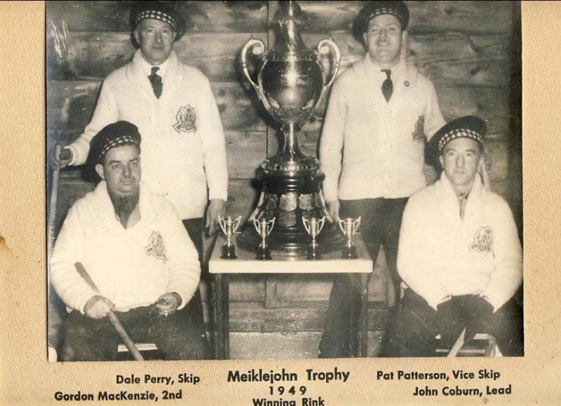 A black and white photo of men holding a trophy from 1949