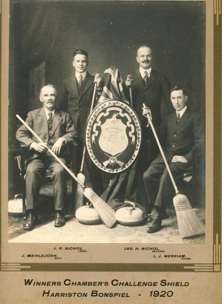 A black and white photo of a group of men holding a shield