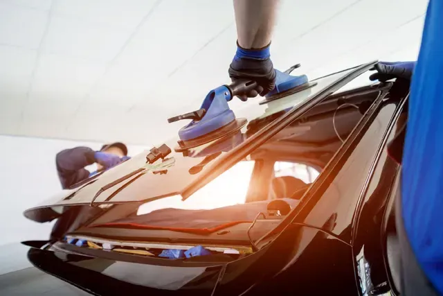 Botas de fútbol azules sobre el techo de un coche al atardecer, con las piernas de una persona visibles cerca.