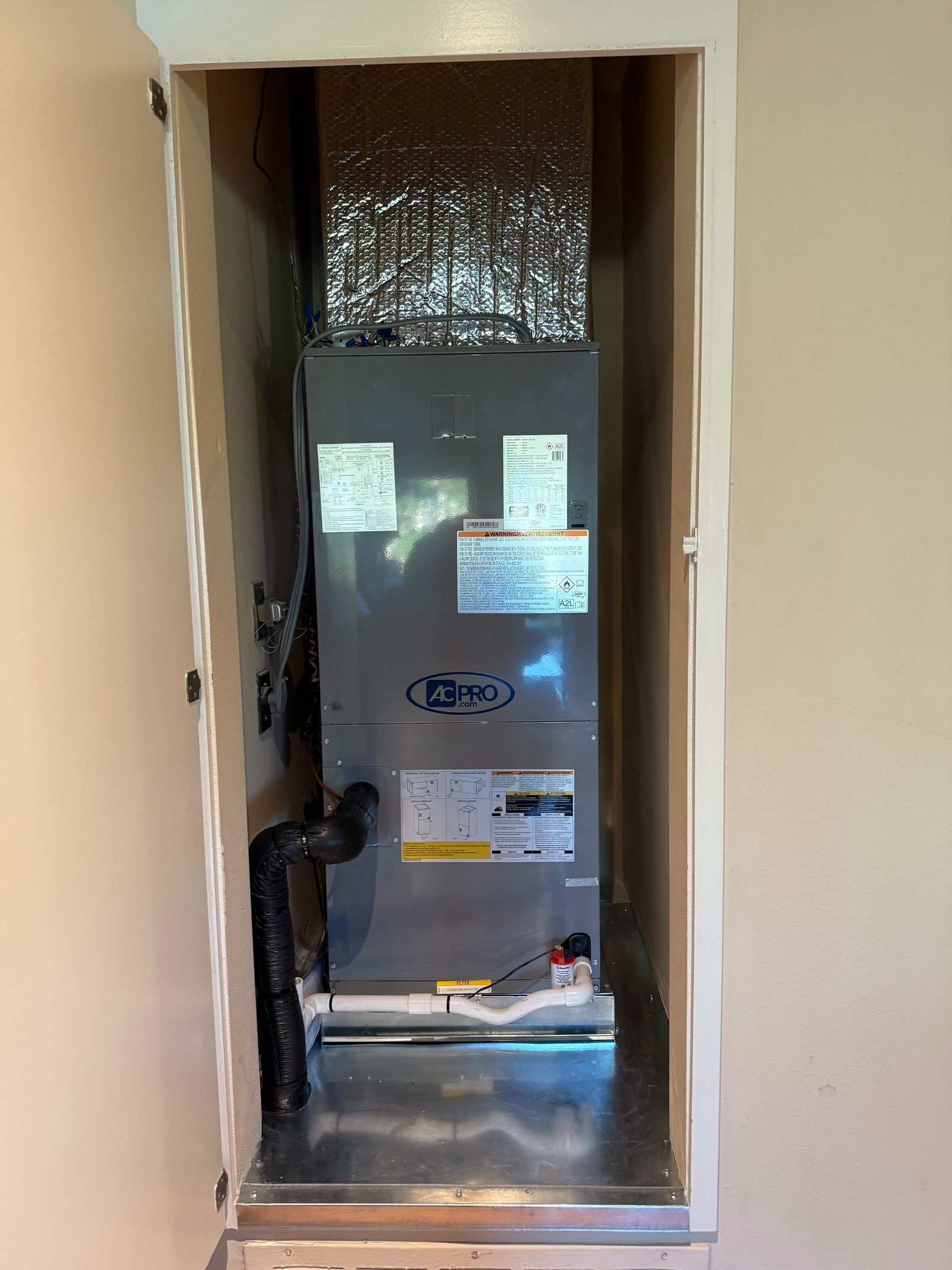 HVAC unit in a wall cabinet, silver metal, with insulated ductwork above.