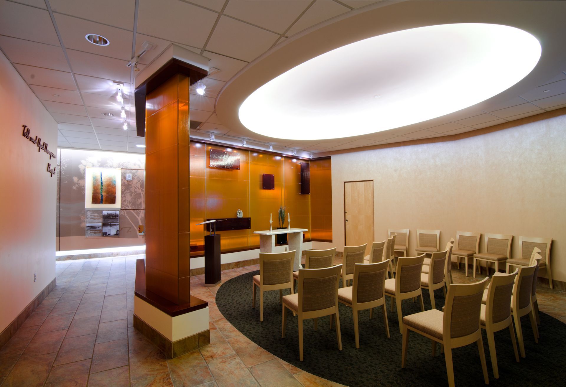 Empty conference room with round ceiling light, beige chairs, and wooden columns