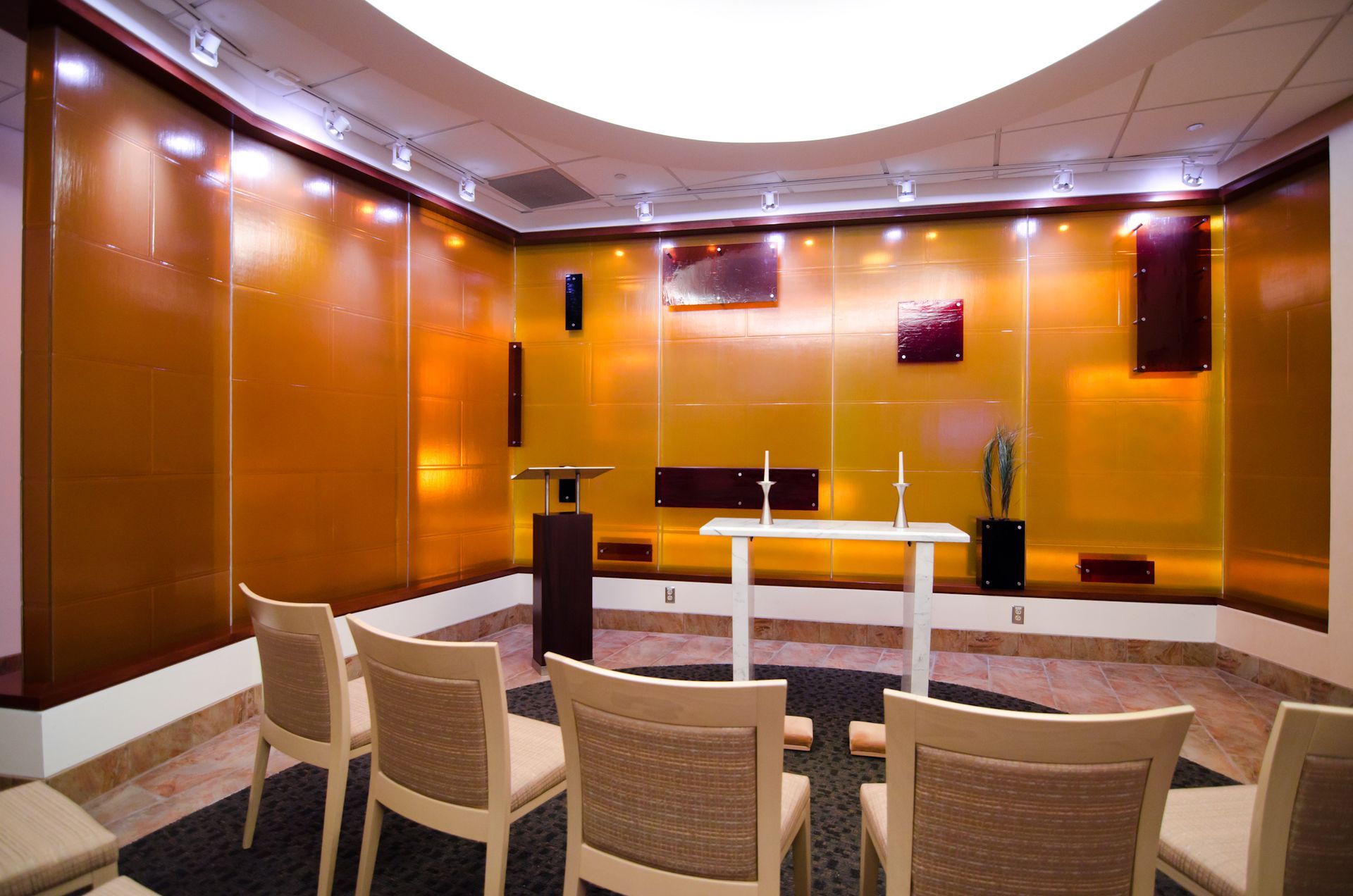 Modern meeting room with beige chairs, a long table, and warm orange wood-paneled walls under recessed lighting