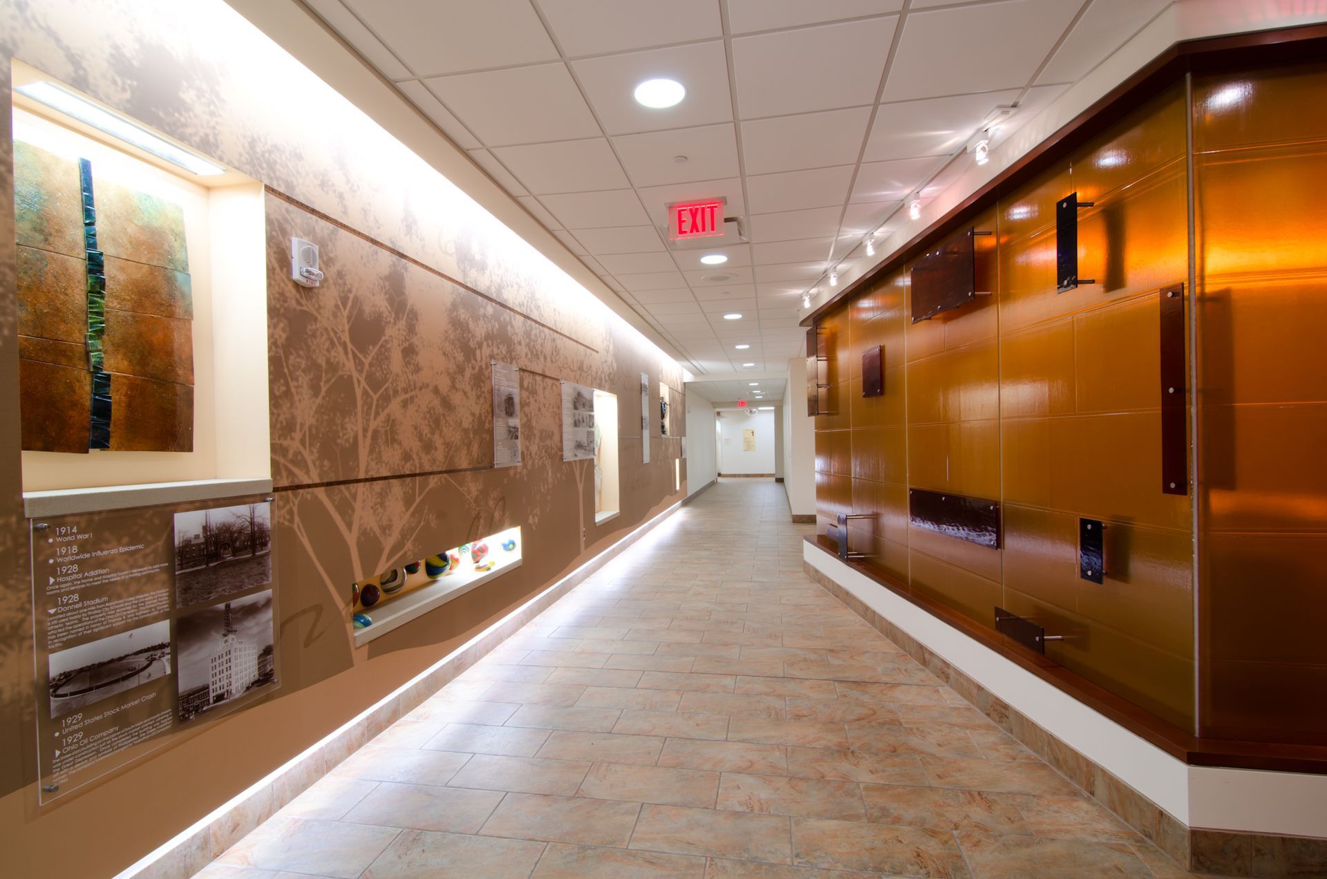 Modern office hallway with beige tile floor, wall art, and glossy brown paneling under bright ceiling lights