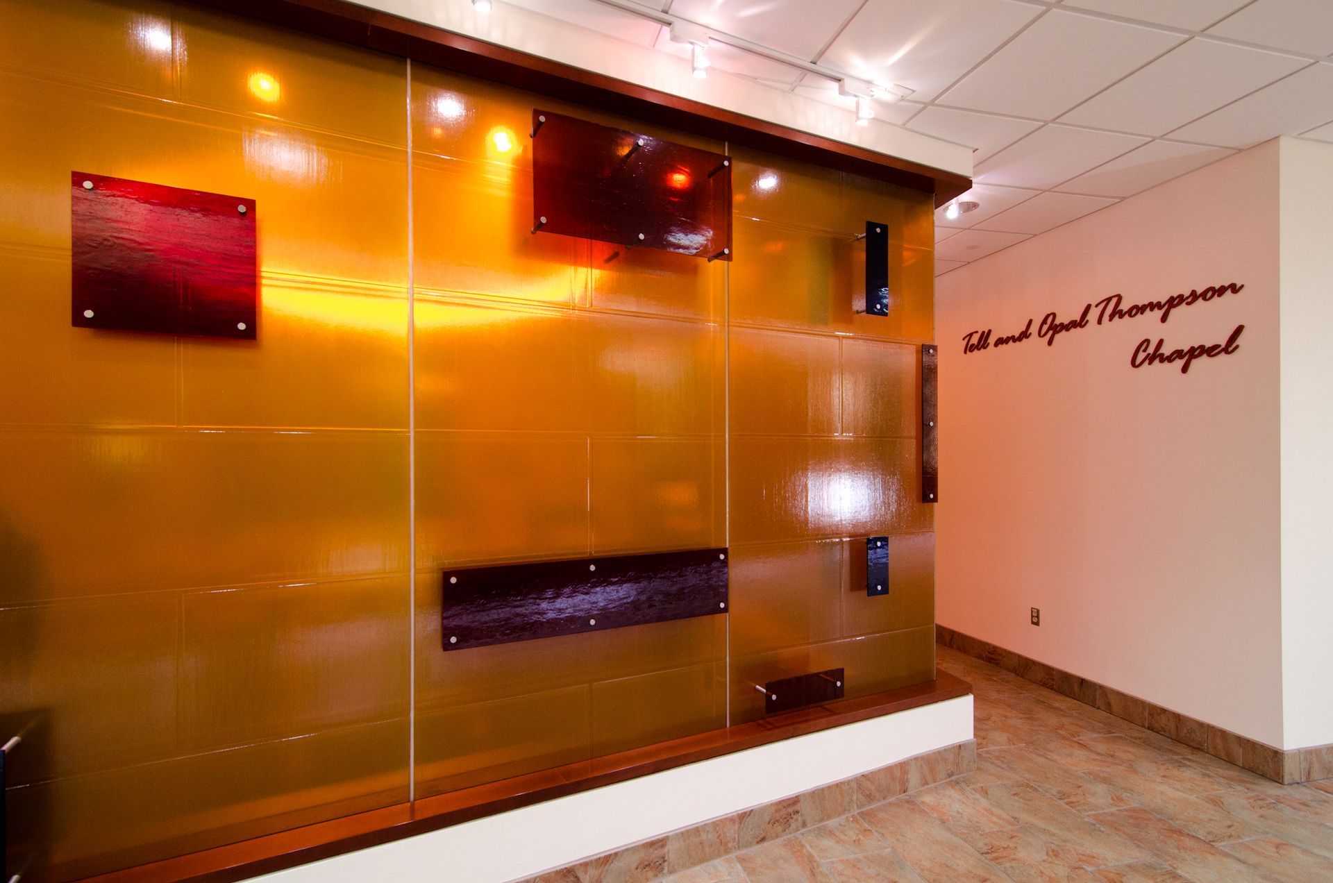 Orange-tinted glass wall with decorative panels in a modern lobby or hallway