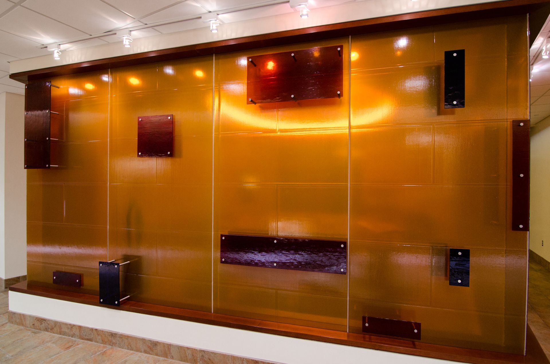 Copper-toned glass wall with small mounted screens in a modern lobby
