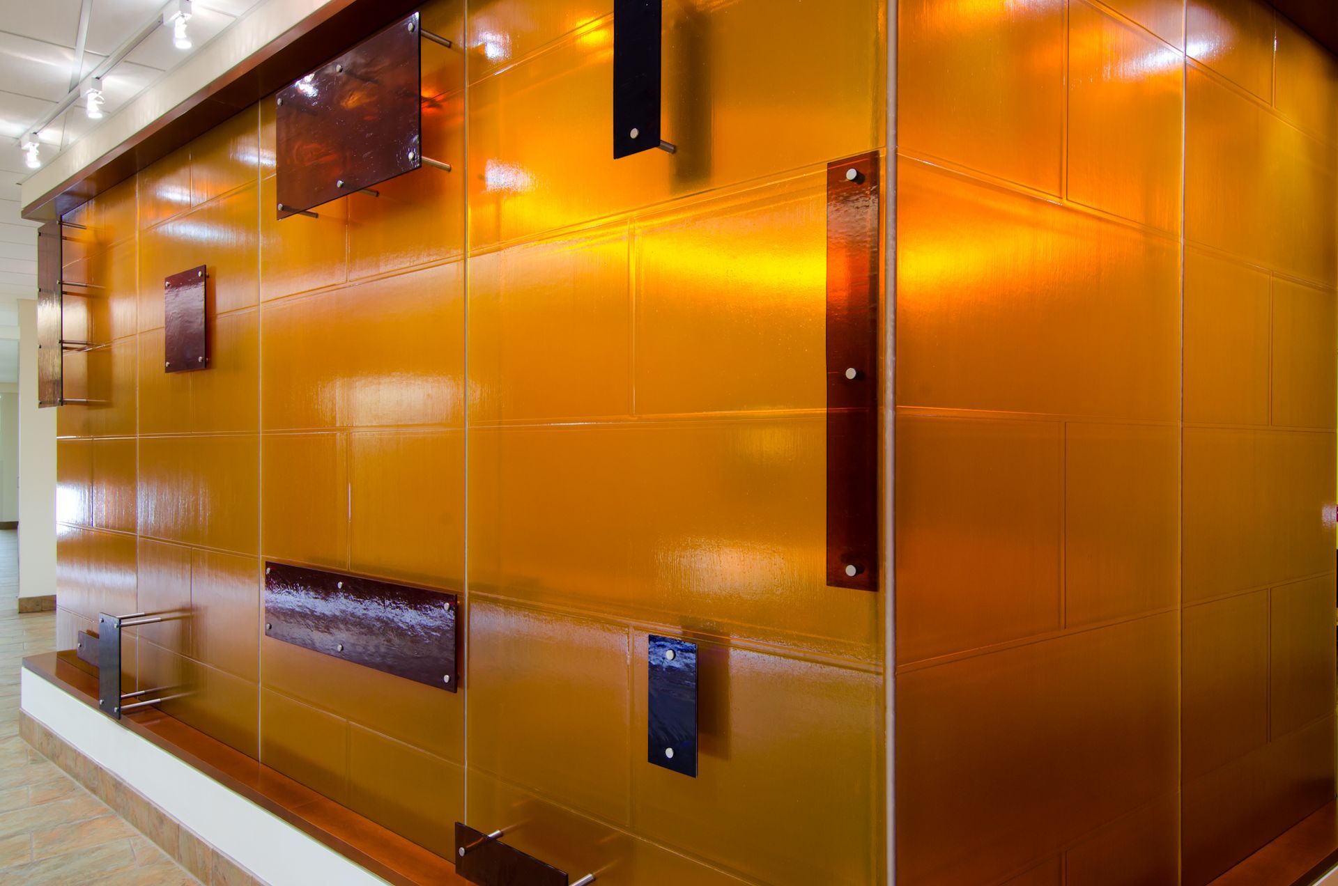 Glossy orange wall panels in a modern interior hallway with glass and metal accents
