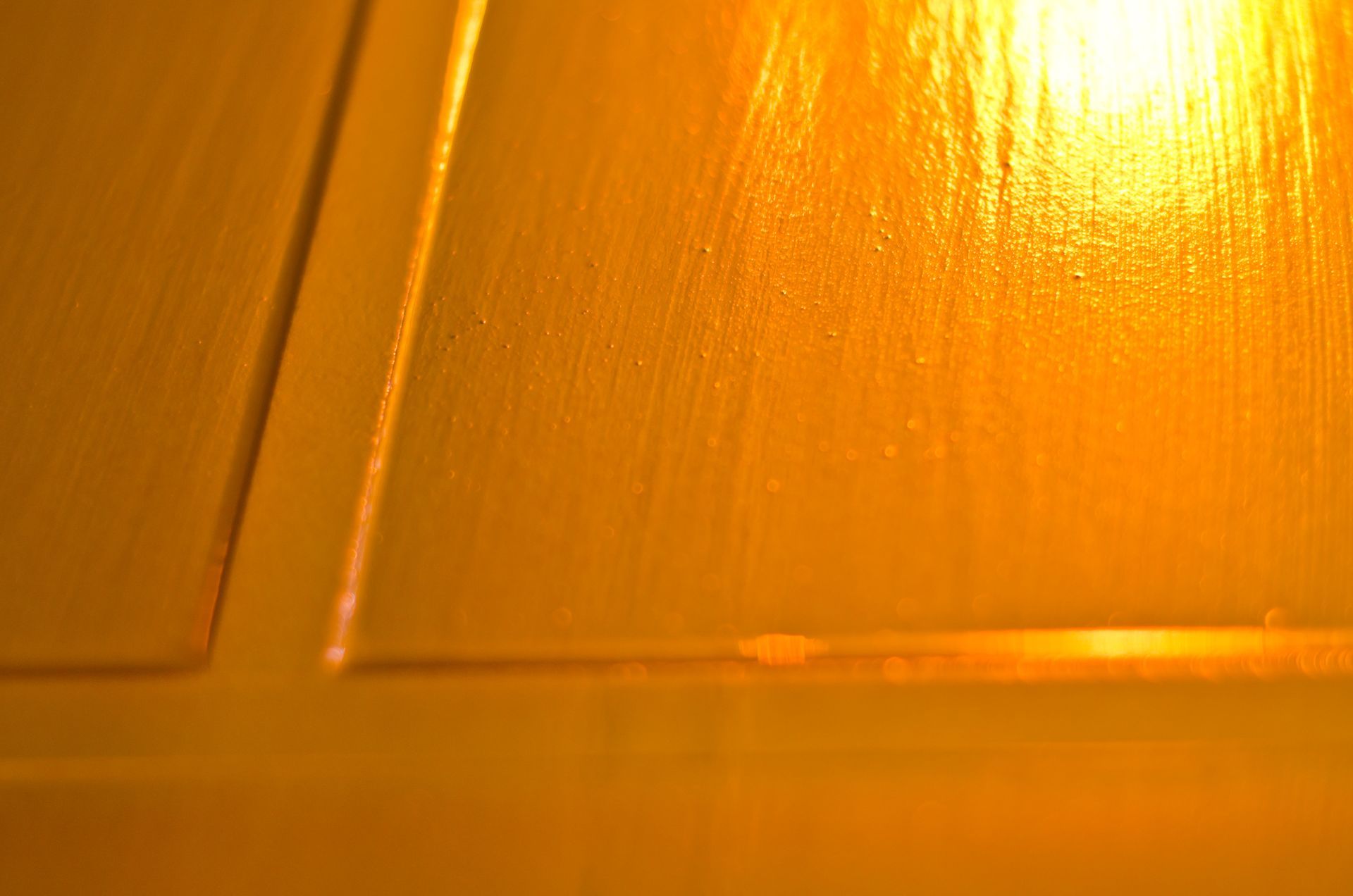 Close-up of a glossy orange surface with a rectangular recessed panel and bright light reflection