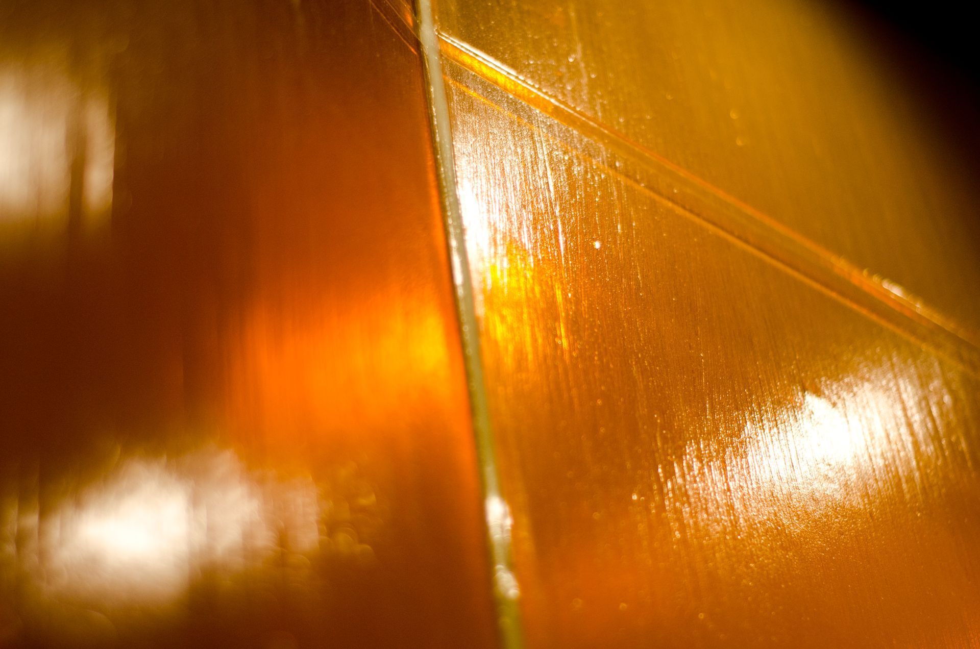 Close-up of a glossy orange-brown surface with bright reflections and a vertical seam
