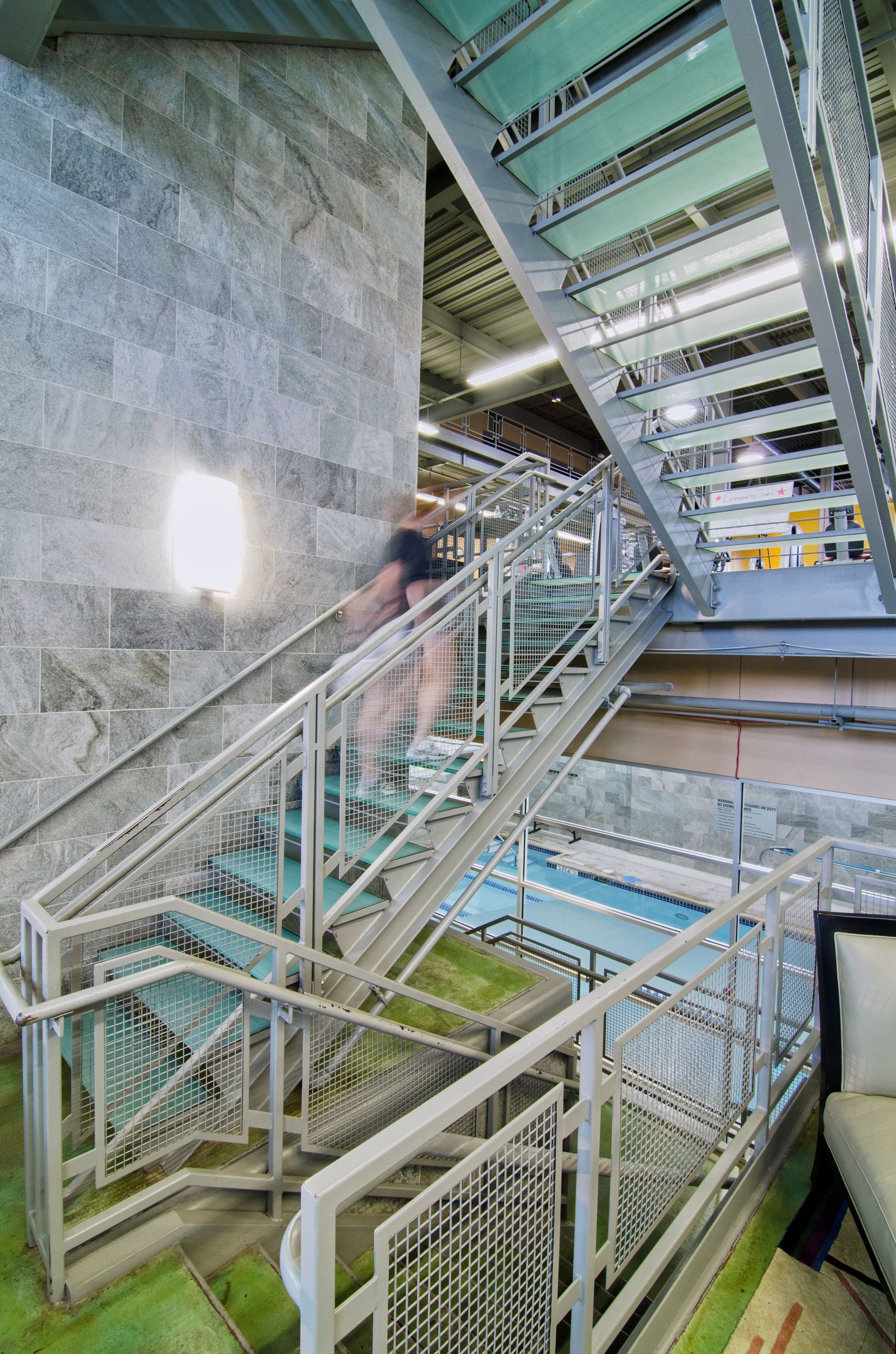 Industrial stairwell with metal railings and a blurred person walking up the stairs