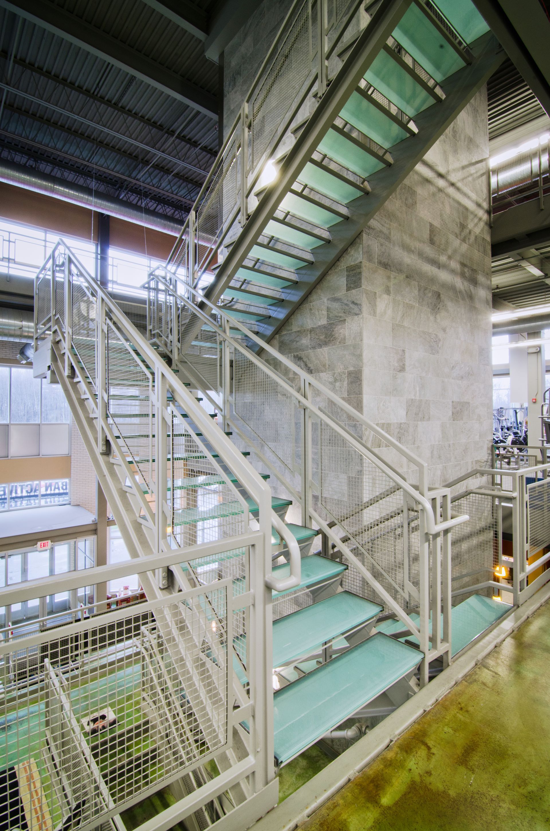 Industrial stairway with green steps and metal railings inside a warehouse-like facility