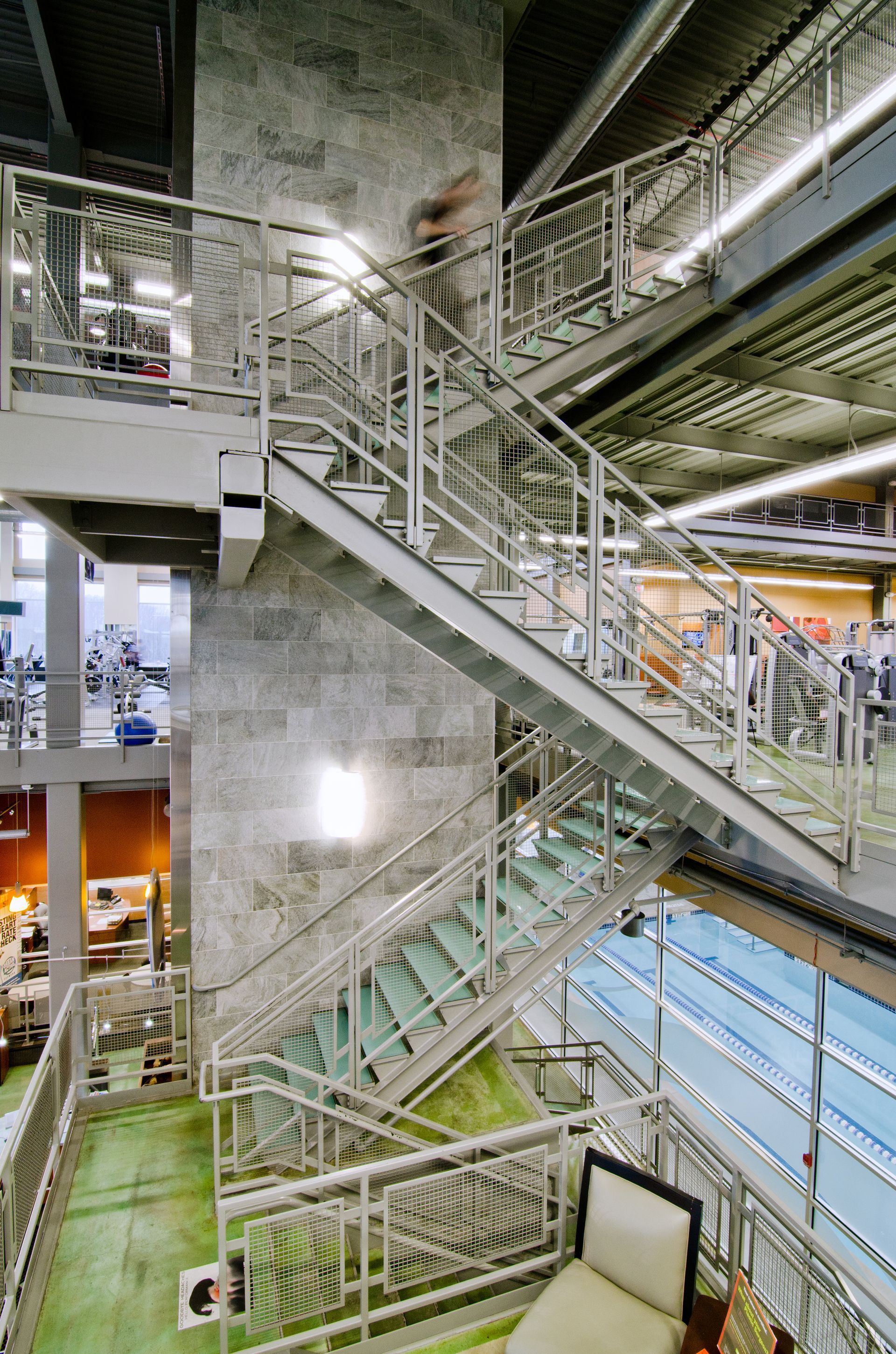 Interior staircase and industrial catwalks in a large building, with metal railings and multiple levels.