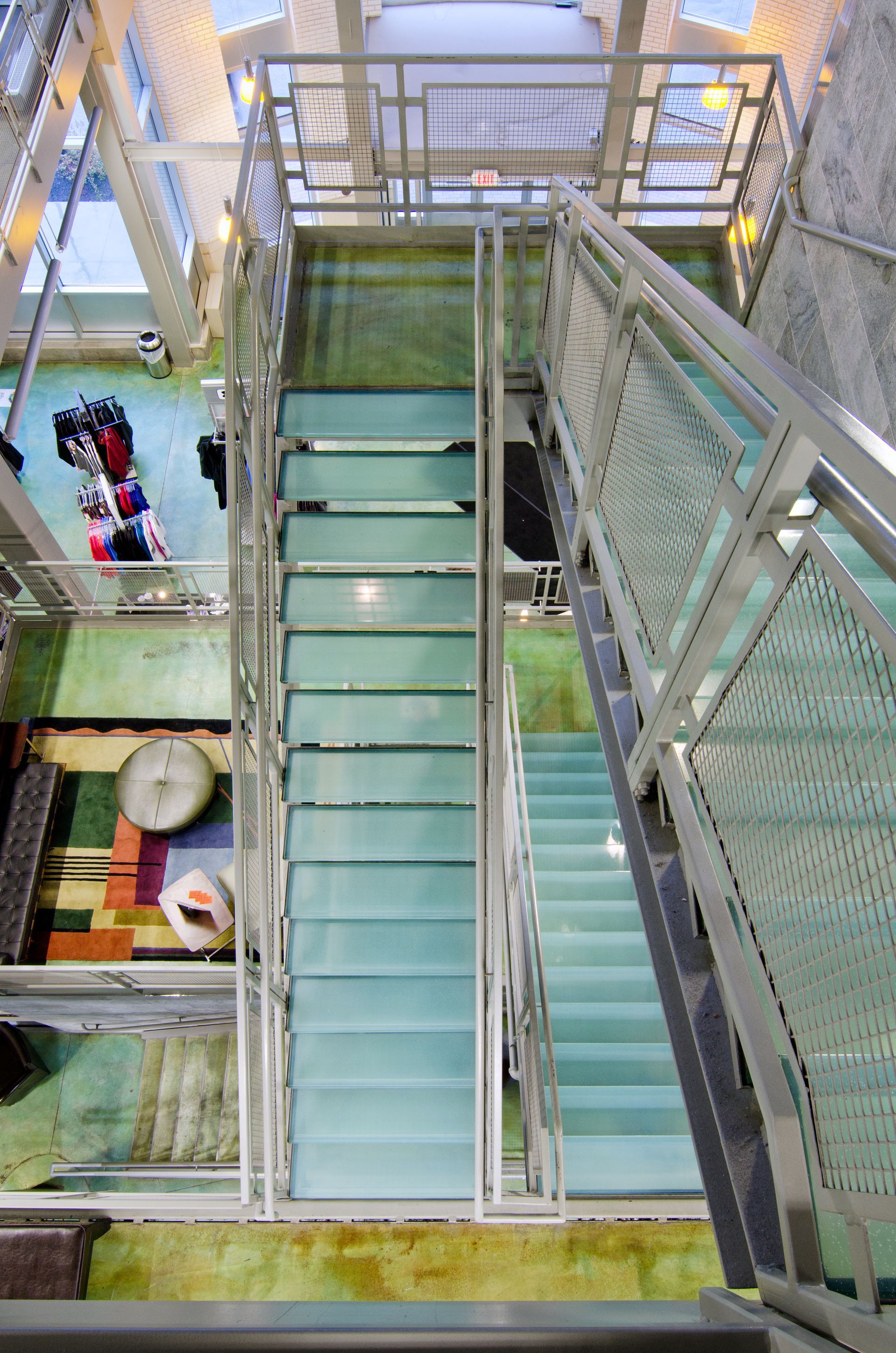 Industrial stairwell with green metal stairs and railings, viewed from above.