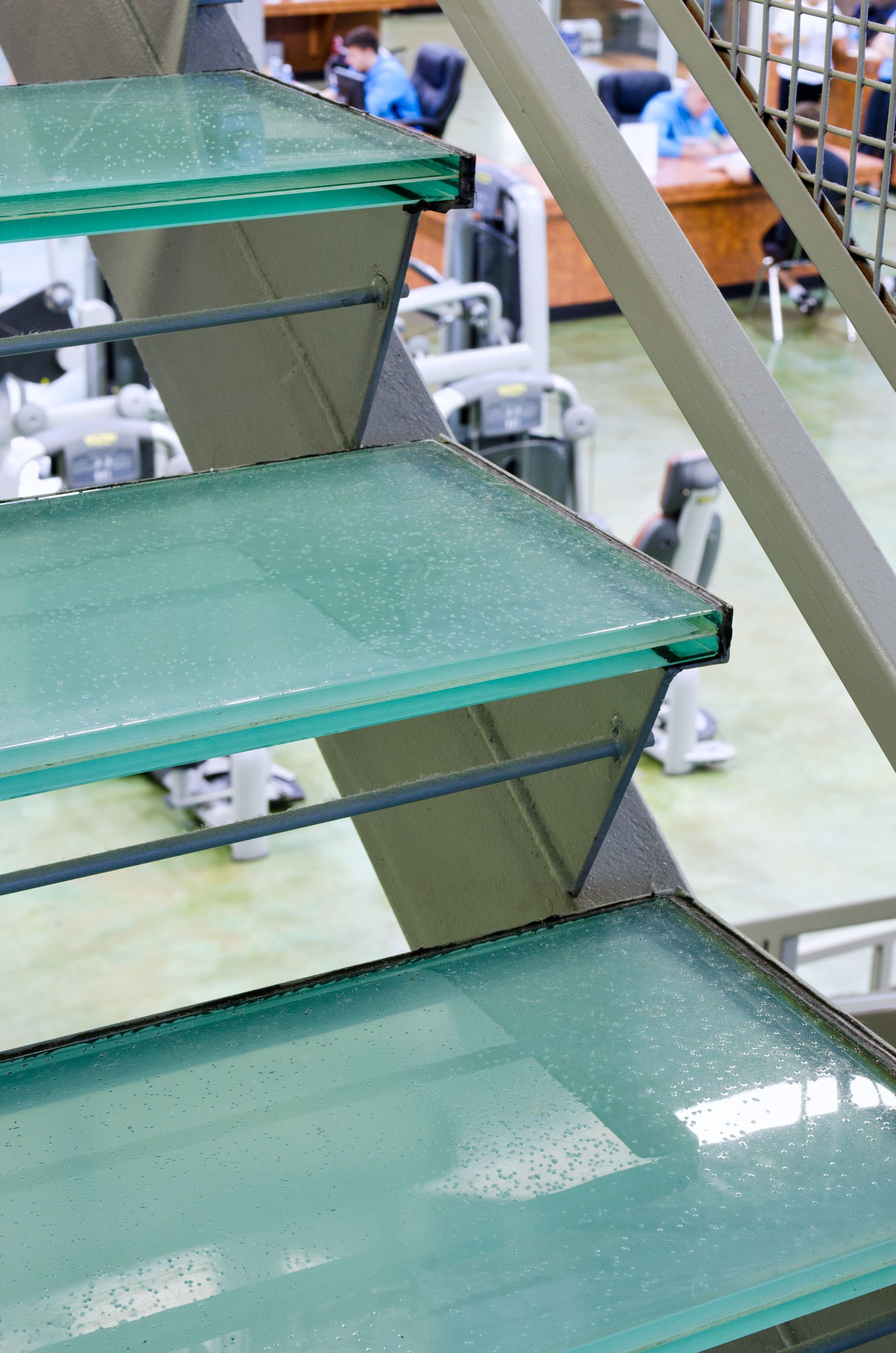 Green metal stairs in an industrial setting, with warehouse equipment in the background