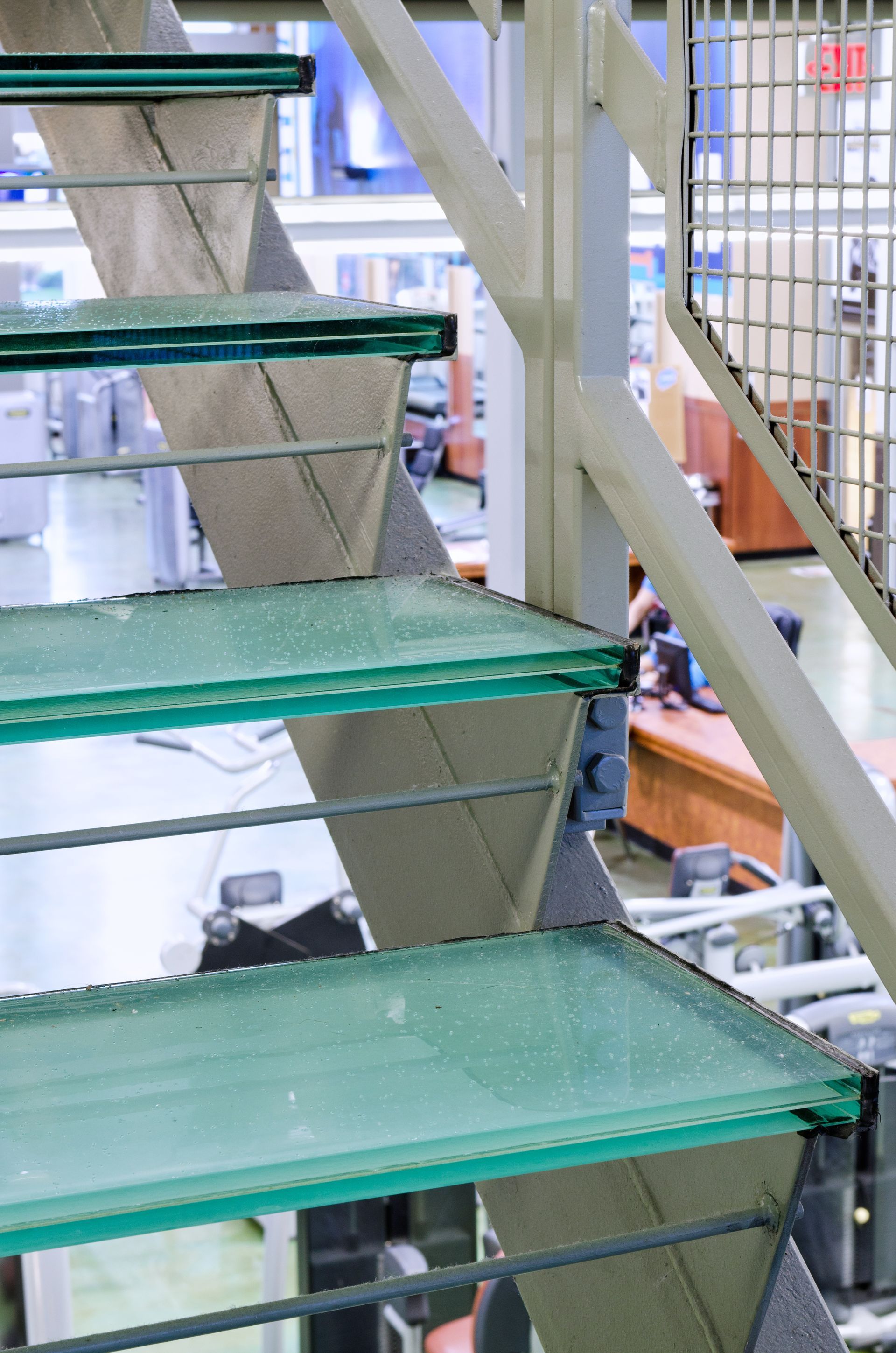 Green metal stairs in an industrial interior, with machinery and storage visible behind them