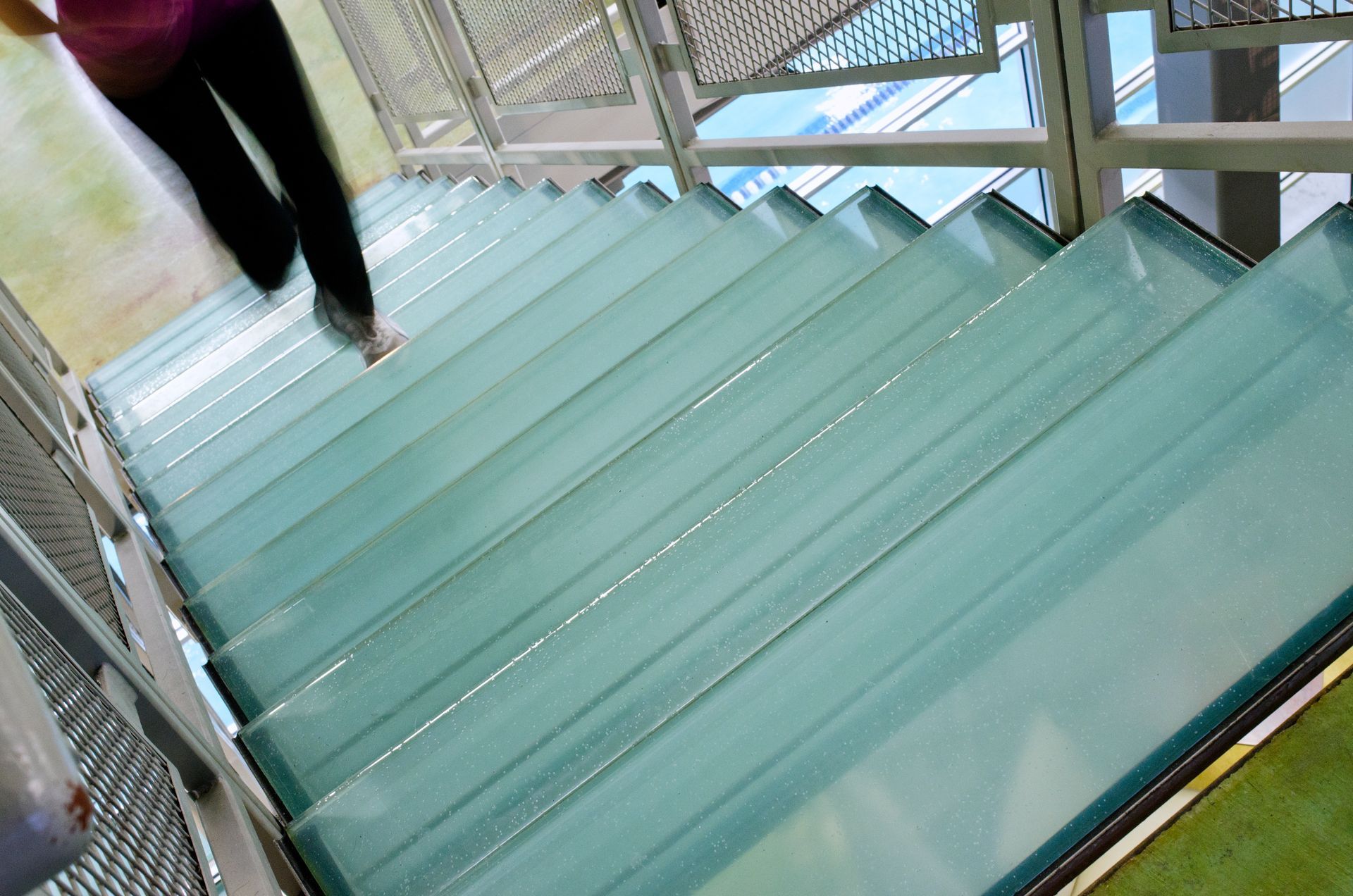 Person descending a glass staircase in a bright modern building