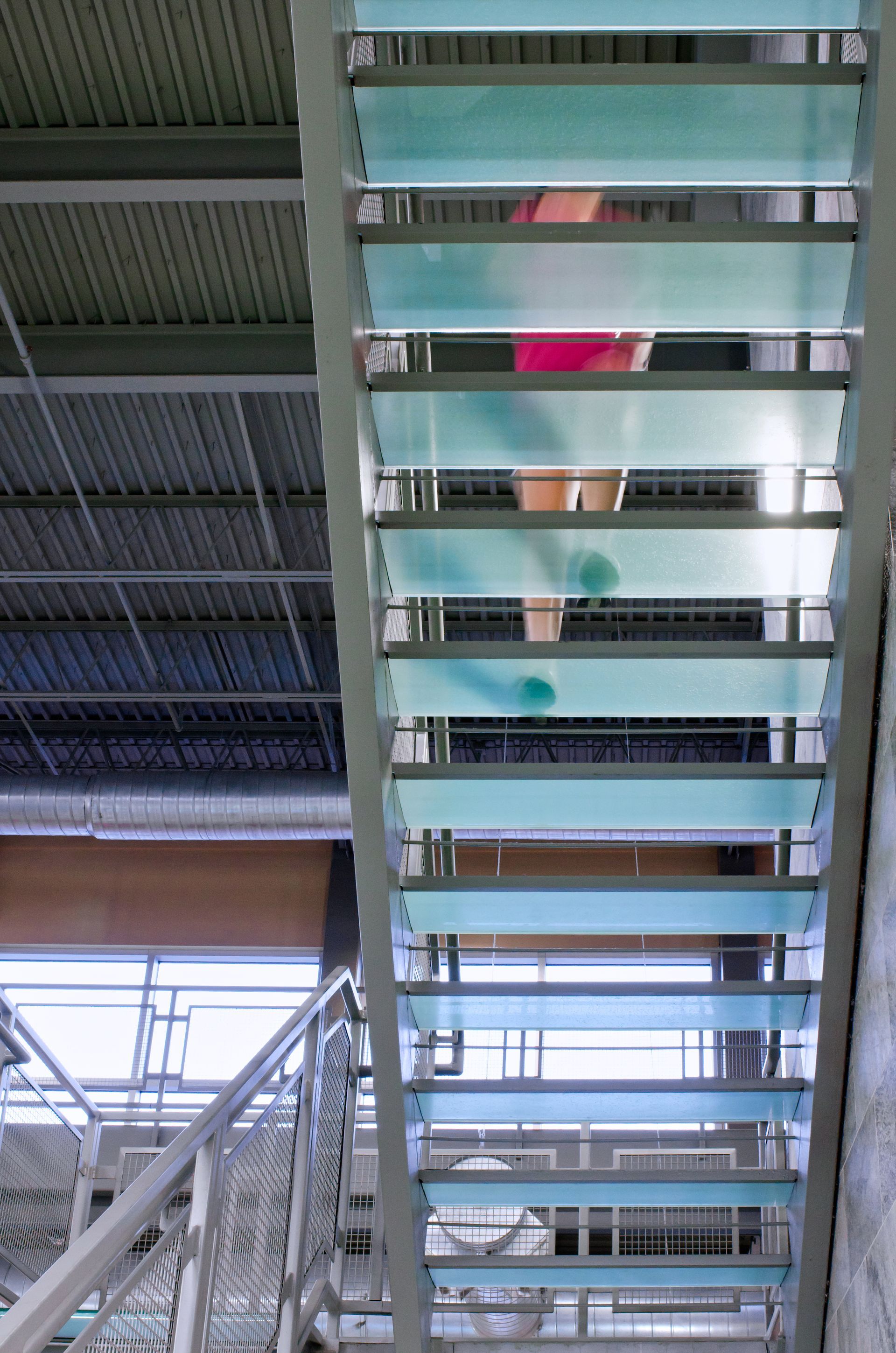 Person in pink top climbing an outdoor metal staircase under a covered structure