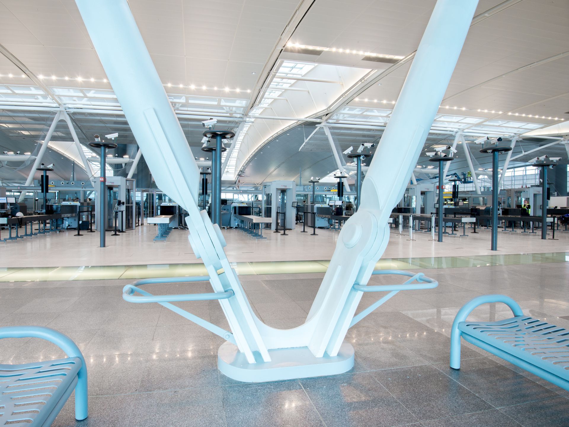 Modern airport terminal with rows of seats and large white support beams under bright lights