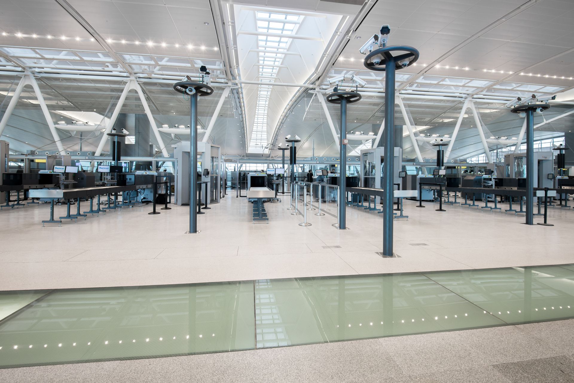 Empty airport terminal with rows of seating and overhead lighting - glass flooring
