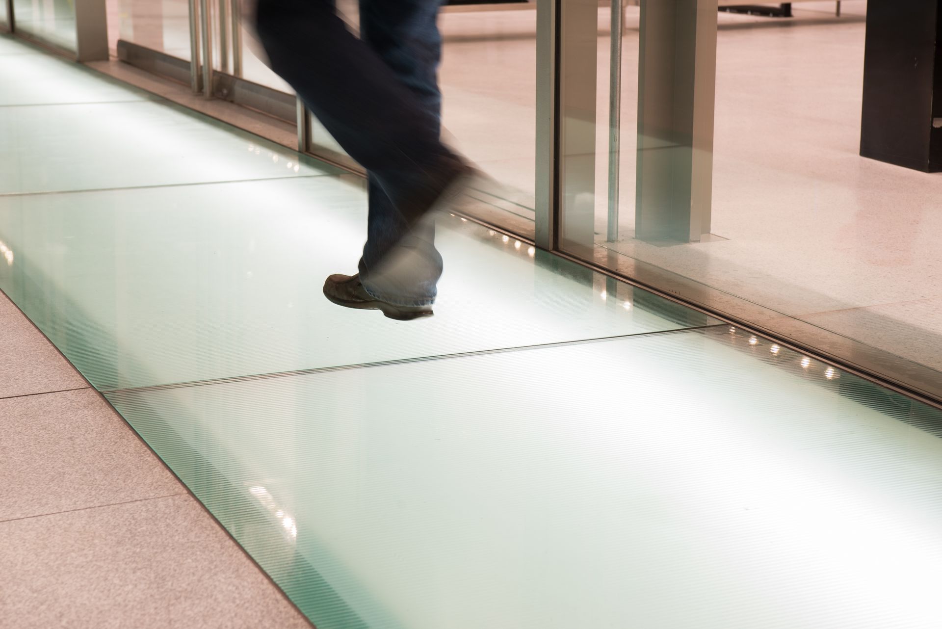 Person walking on a glass floor panel indoors