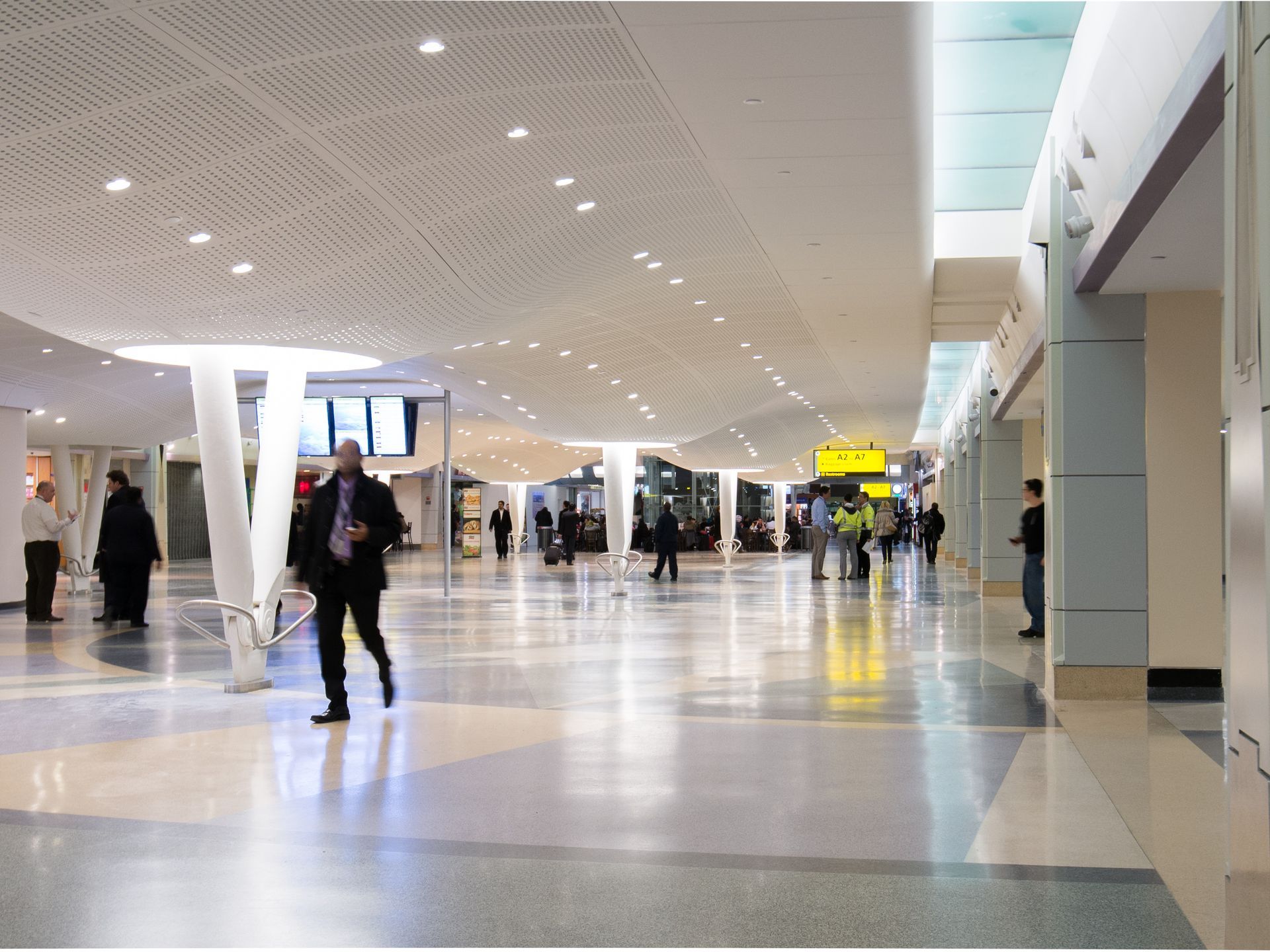 Spacious airport concourse with scattered travelers, bright overhead lights, and glossy floors