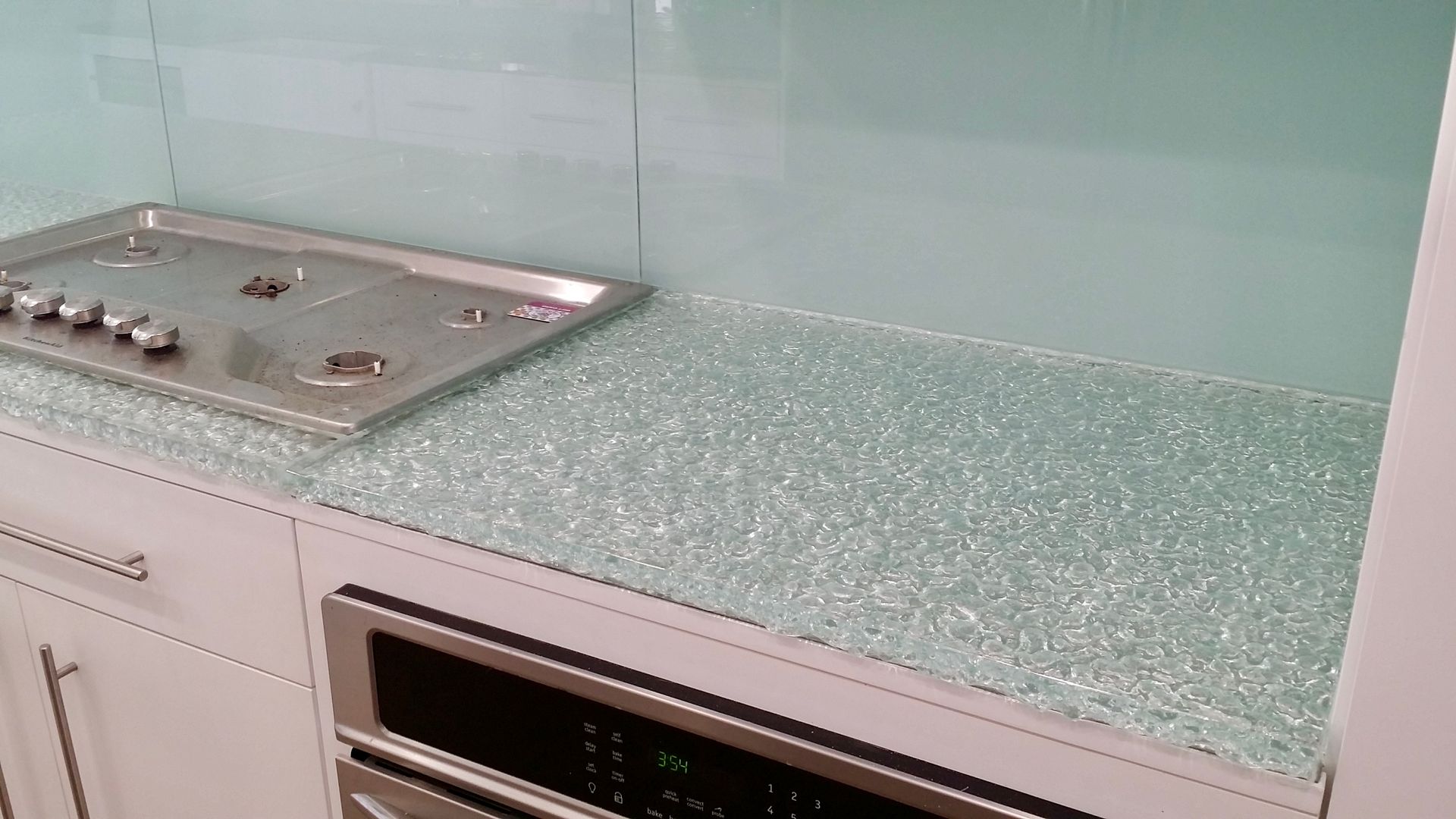 A kitchen with a stove top oven and a glass counter top.