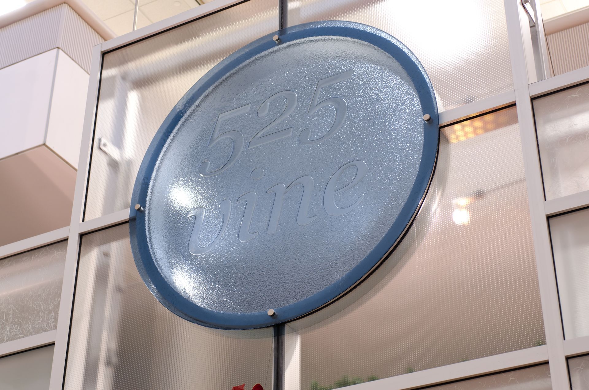 Large blue circular sign mounted on a building facade above glass windows