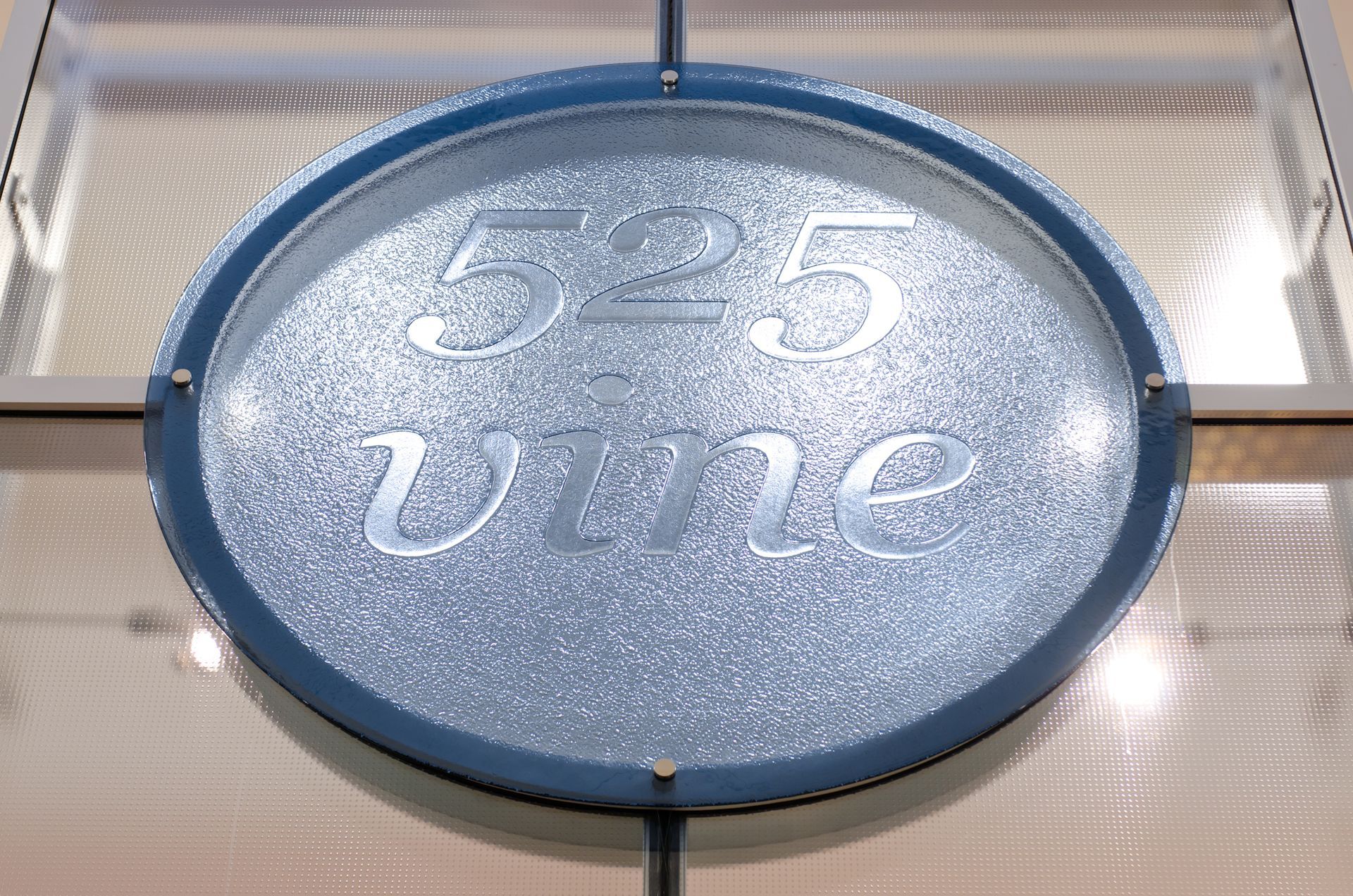 Blue circular sign with “525” and “uine” in white, mounted on a wall.