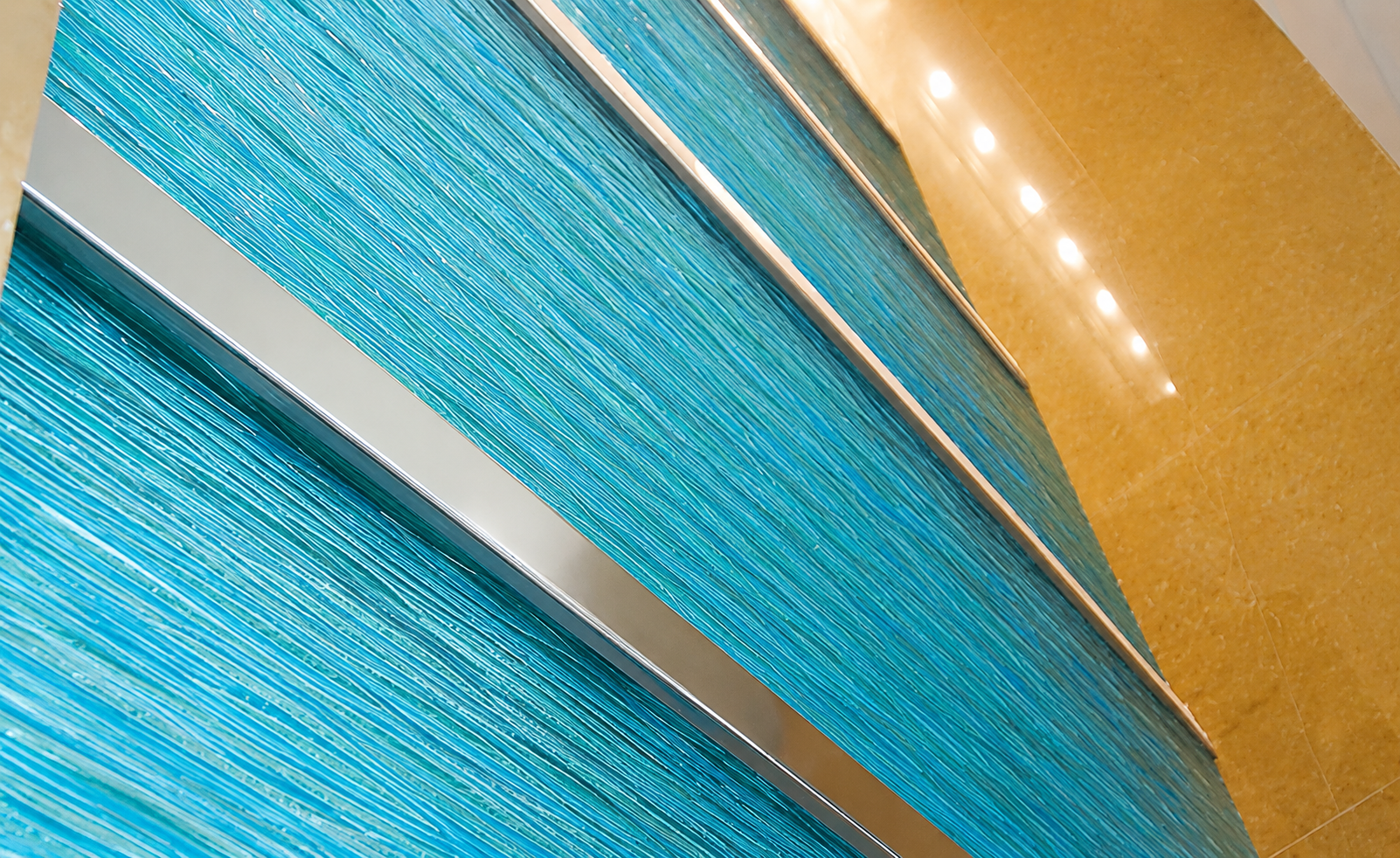 Blue and silver diagonal architectural panels beside a warm wooden wall with small lights