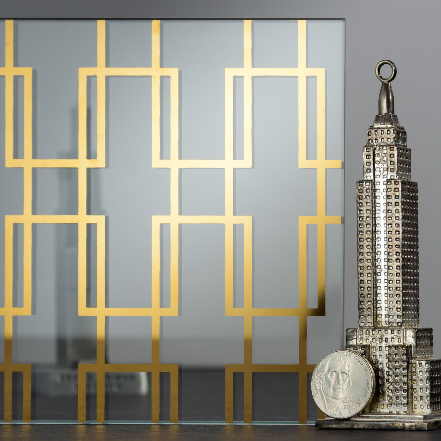 Gold geometric design on glass with Empire State Building statue and coin.
