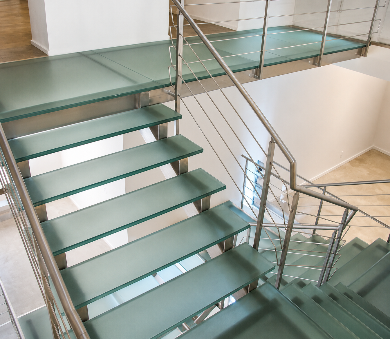 Glass staircase with green steps and metal railings in a bright indoor building