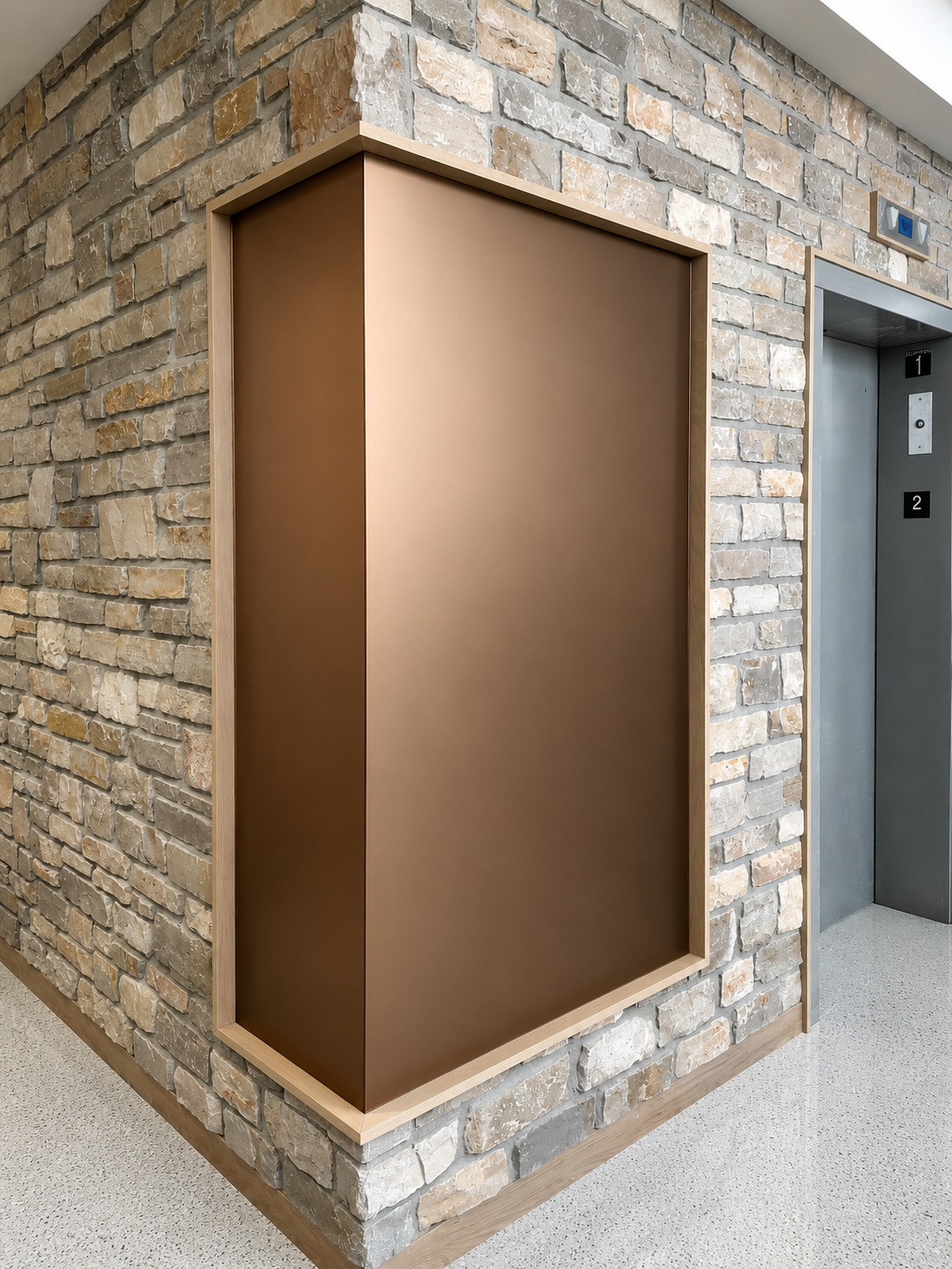 Empty bronze wall niche in a stone hallway beside an elevator.