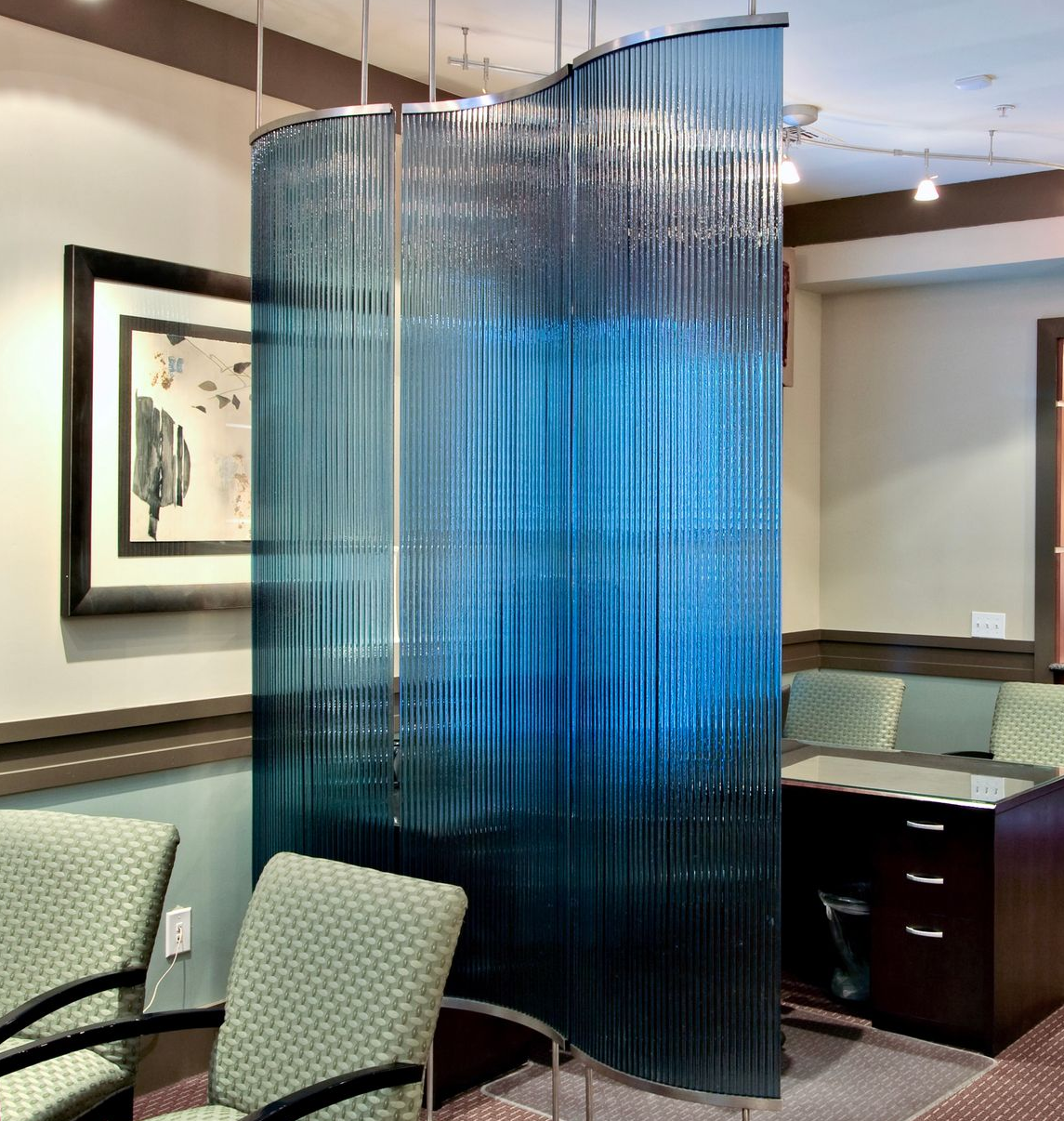 Curved blue privacy screen in a waiting room with chairs and a desk