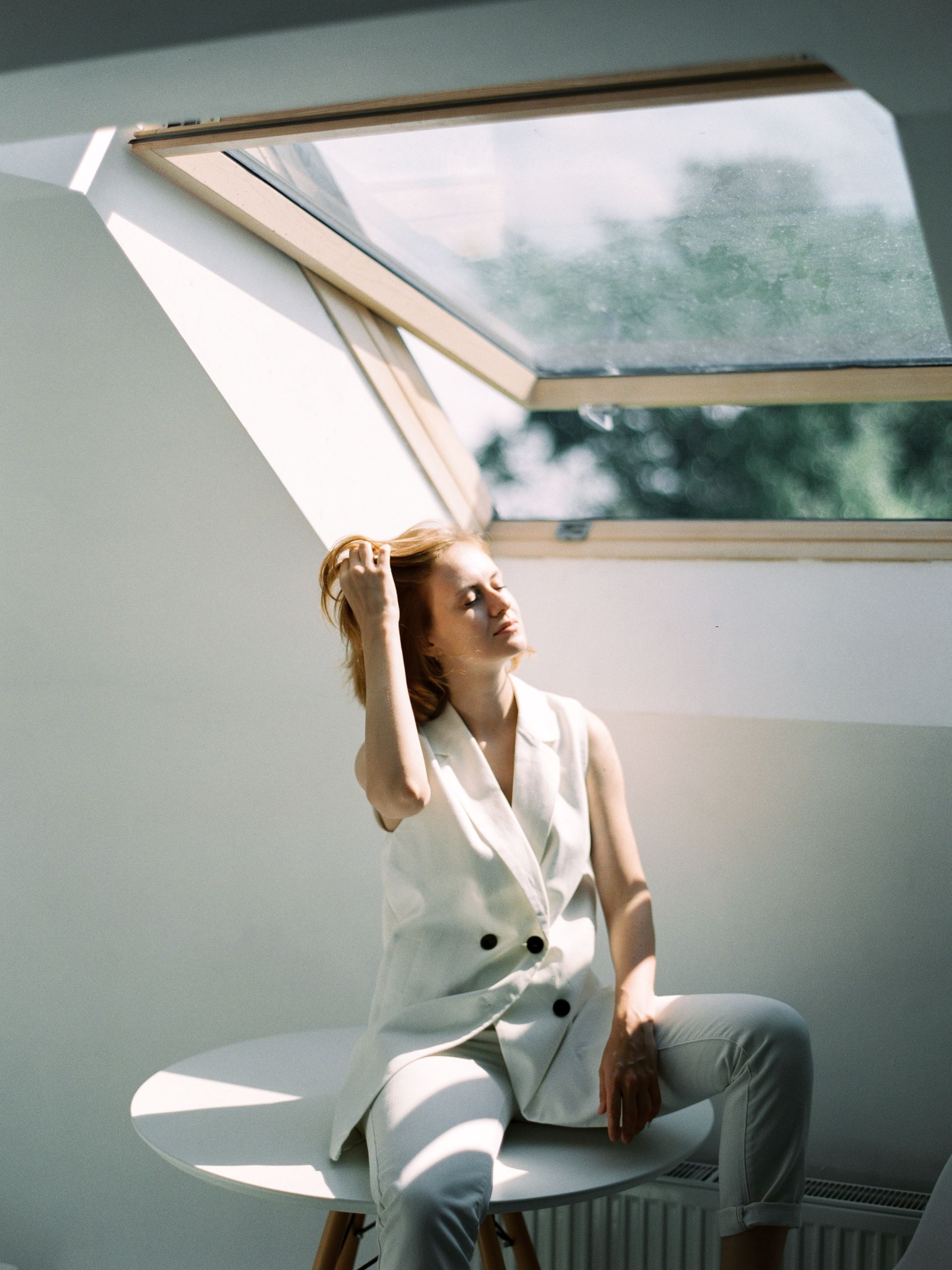 A woman sitting underneath an open window with sunlight pouring in. A woman sitting underneath an open window with sunlight pouring in.